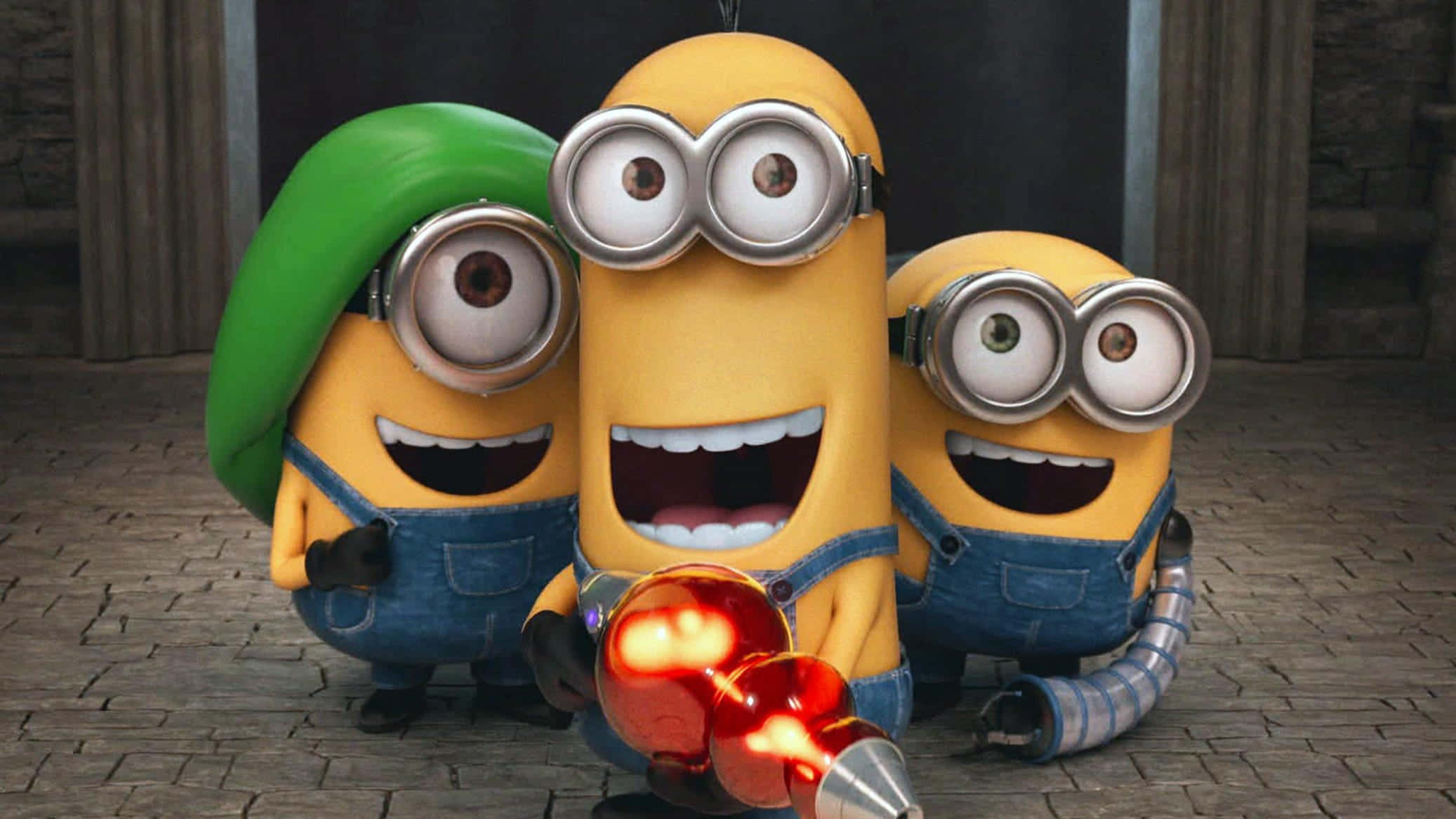 Minion 桌布 壁紙 — 三個穿著藍色工裝褲的開心黃色Minions在石地板上拿著發光的紅色武器大笑。