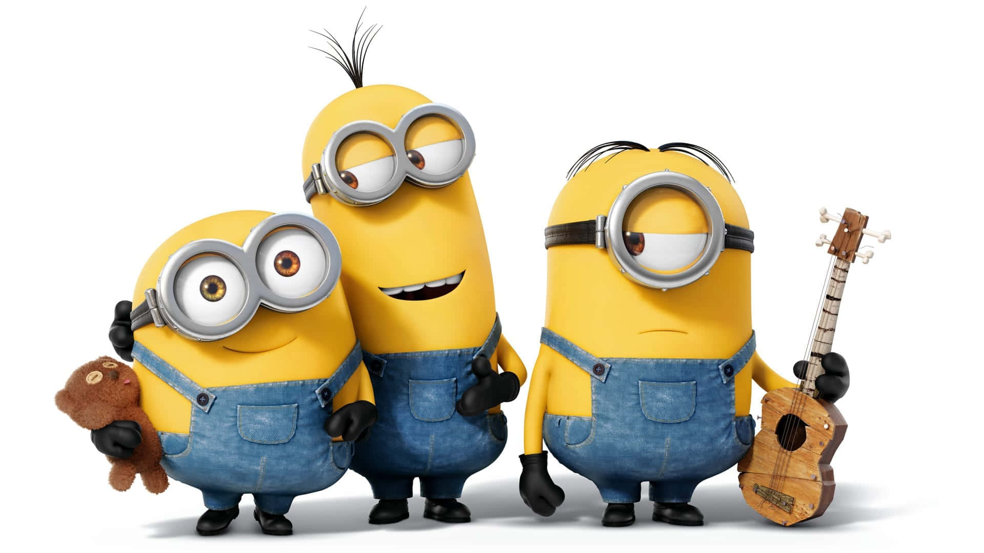 小黃人 桌布 壁紙 — 三個穿著藍色工裝褲的開心黃色Minions，在純白色背景前與泰迪熊和烏克麗麗擺姿勢。