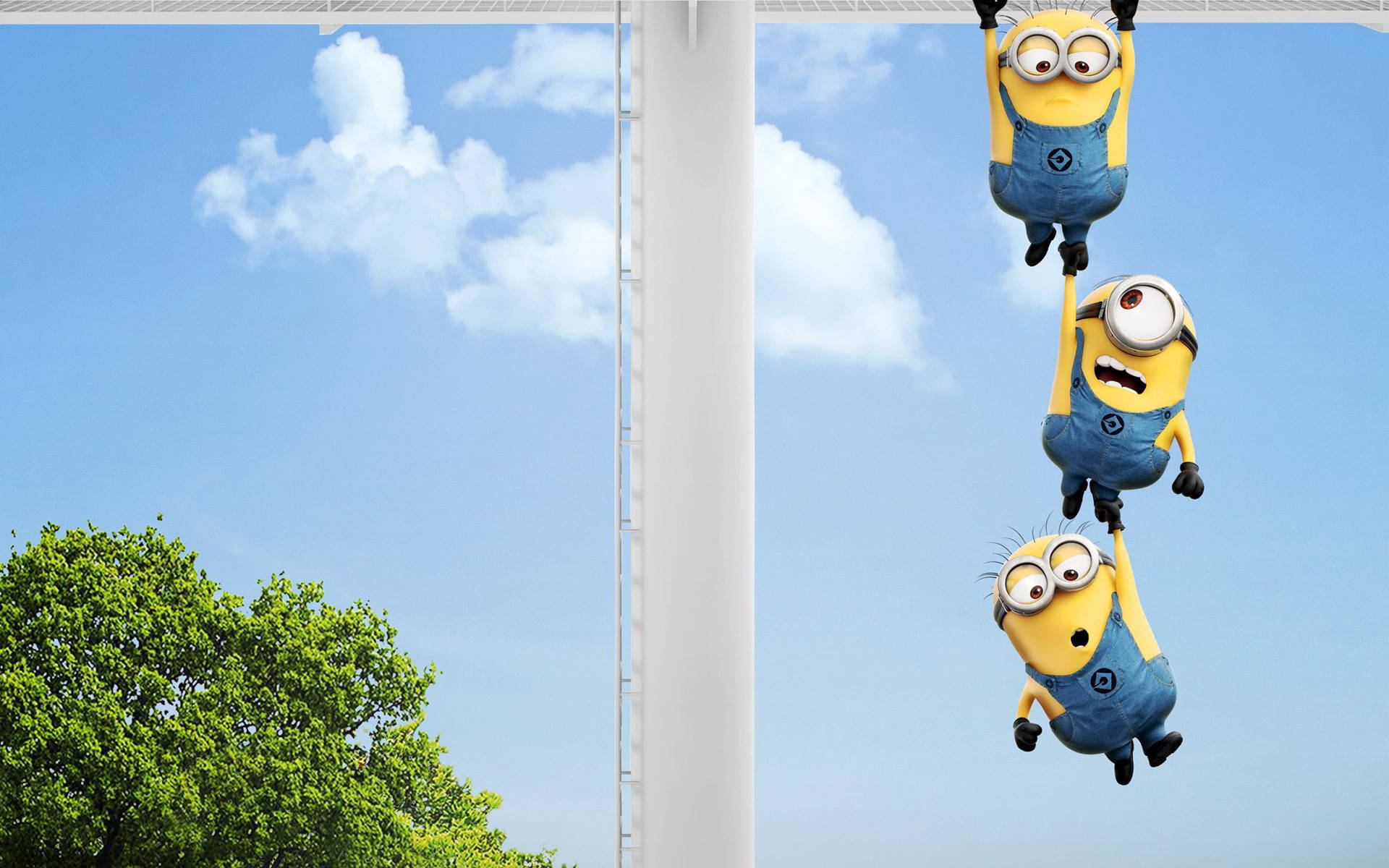 Despicable Me 2 桌布 壁紙 — 三個穿著藍色工裝褲的黃色Minions倒掛在白色桿子上，背景是明亮的藍天、蓬鬆的白雲和下面的綠樹。