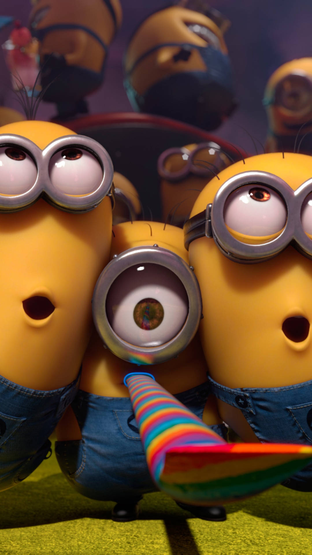 Despicable Me 2 桌布 壁紙 — 三個穿著藍色工裝褲的黃色小小兵睜大眼睛凝視，其中一個拿著彩虹派對喇叭。