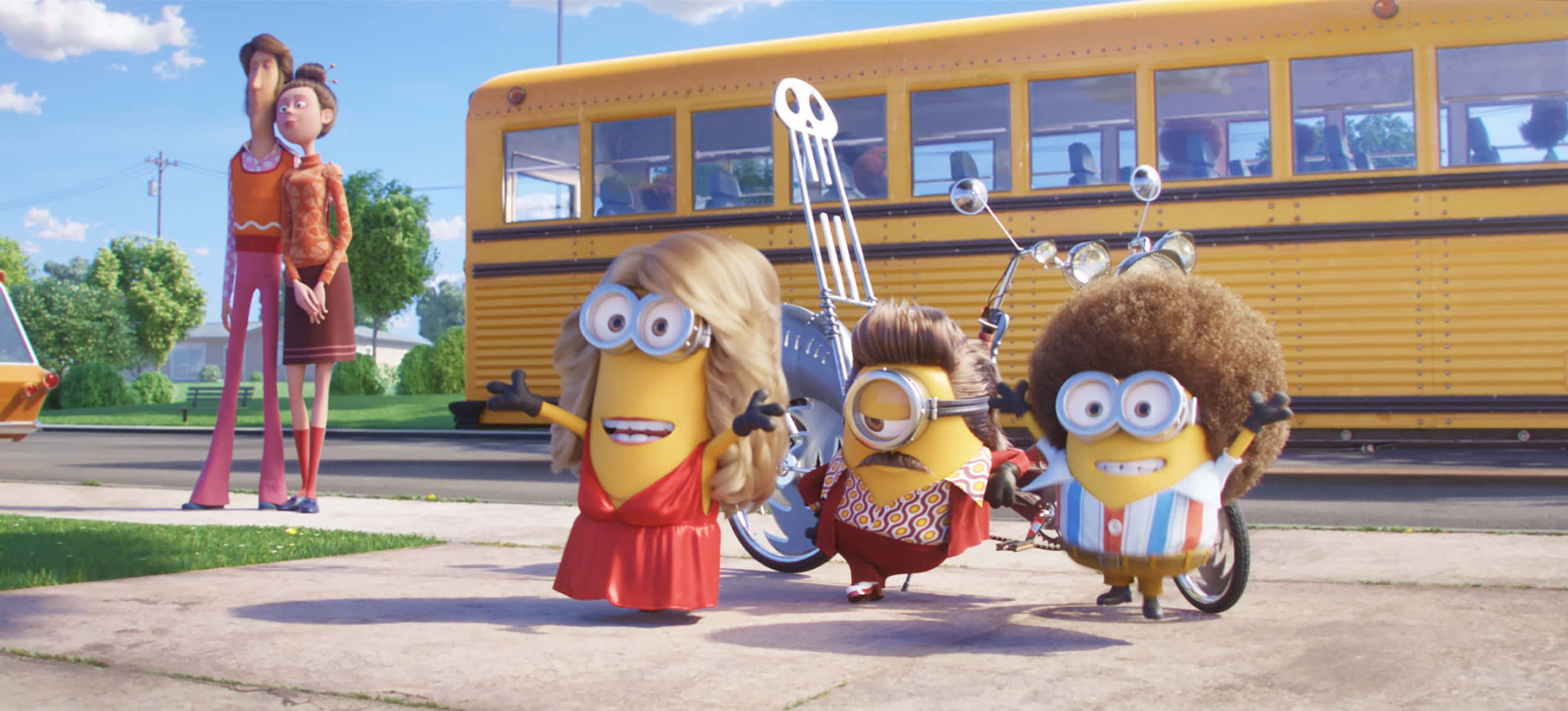Minion 桌布 壁紙 — 三個穿著閃亮服裝的迷你兵團在明亮的藍天下，開心地在一輛黃色校車旁擺姿勢。