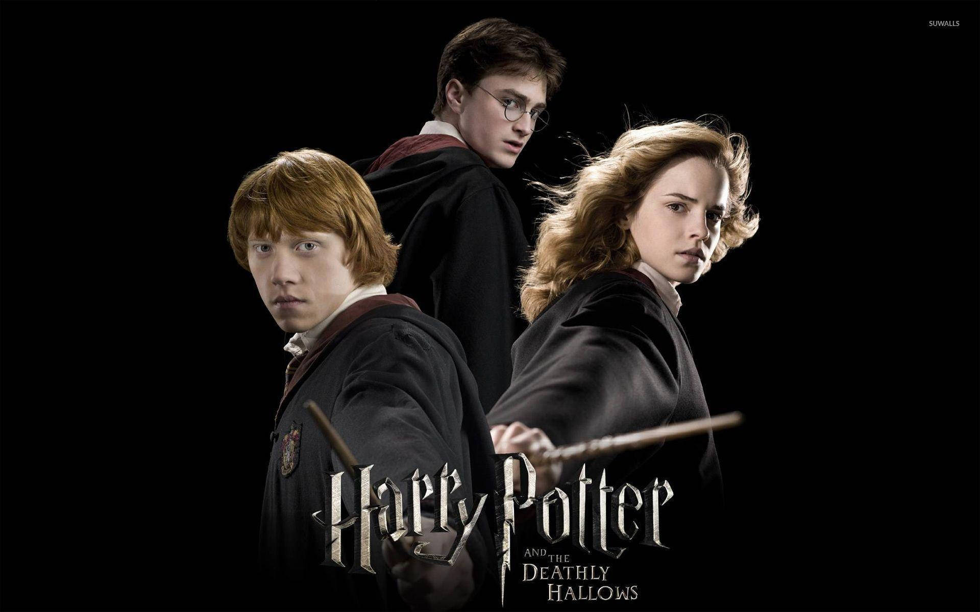 Ron Weasley 桌布 壁紙 — 三個穿著霍格華茲長袍的哈利波特角色站在黑色背景前，手持魔杖，下方有電影標題。