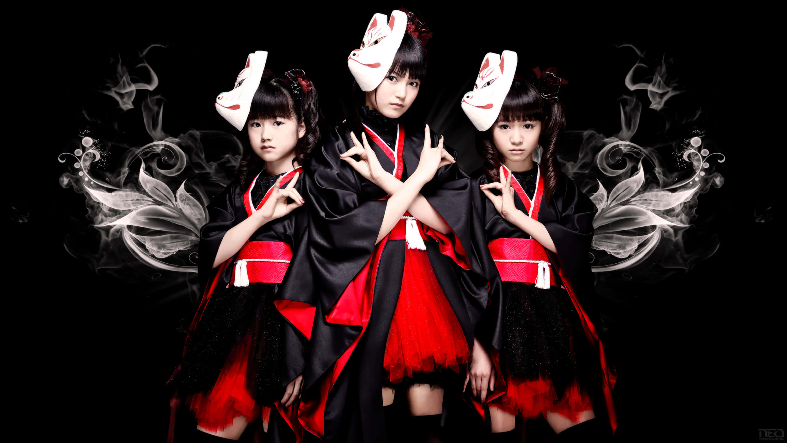 J-rock 桌布 壁紙 — 三個穿著黑紅和服、戴著狐狸面具的女孩在黑暗背景前擺姿勢，背景有旋轉煙霧效果。
