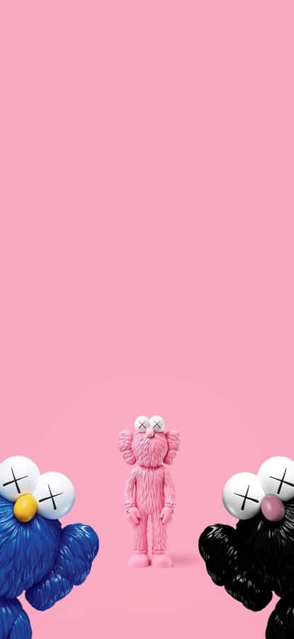 Cool Kaws 桌布 壁紙 — 三個粉紅色、藍色和黑色的KAWS毛絨公仔站在純粉紅色背景前。