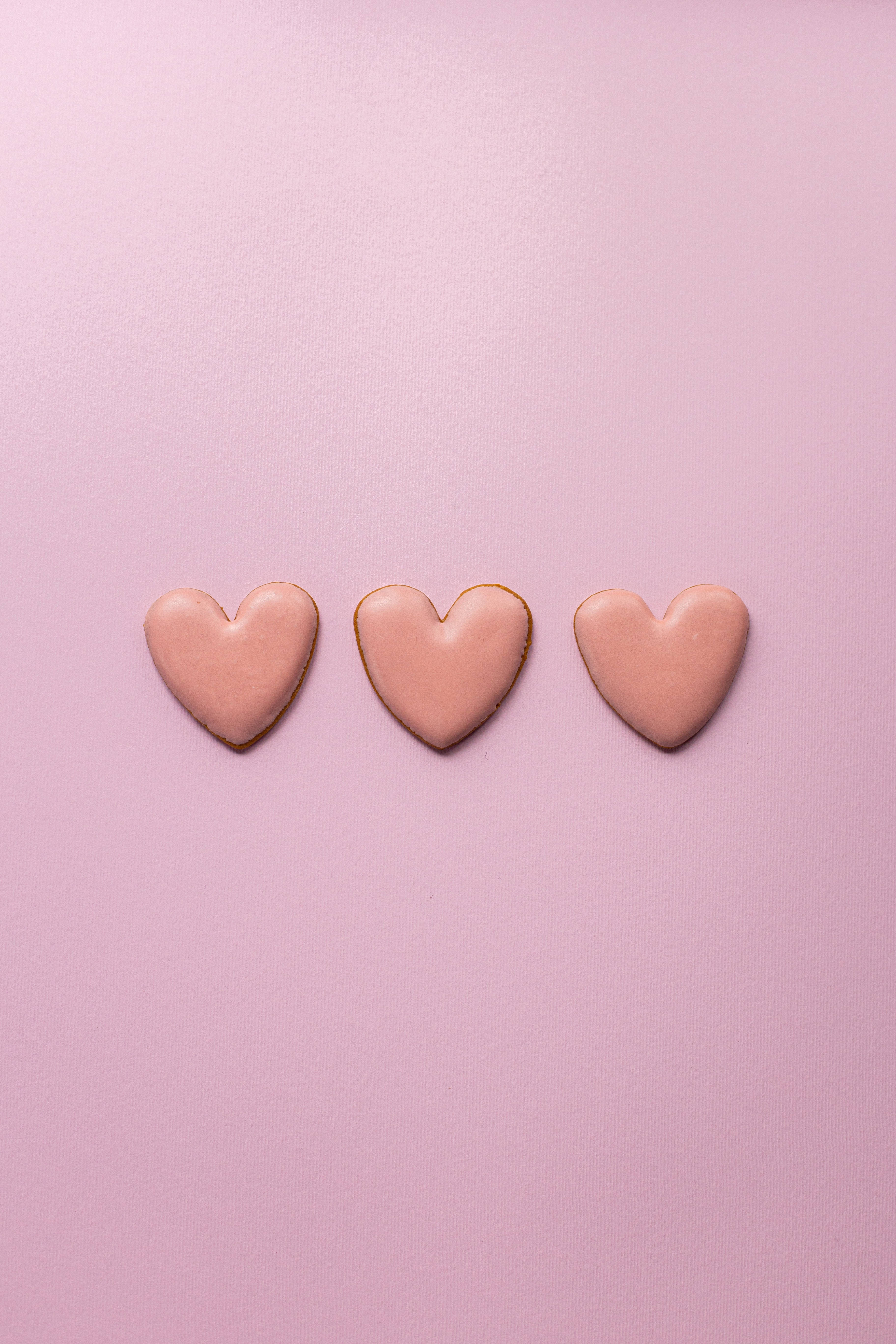 Pastel Pink Heart 桌布 壁紙 — 三個粉紅色糖霜心形餅乾排列成一行，放在柔和的薰衣草背景上。
