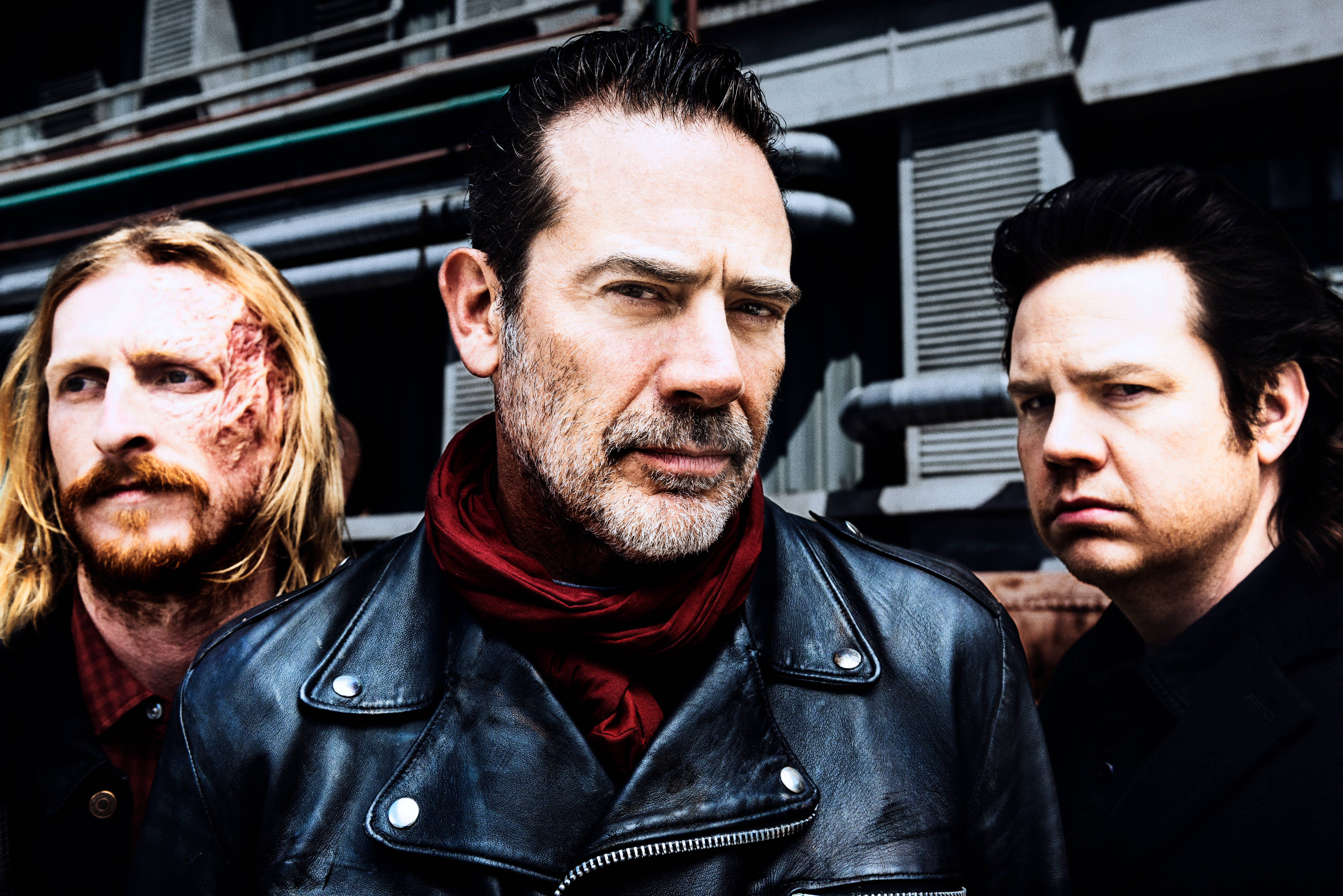 Negan 桌布 壁紙 — 三個粗獷的男人帶著強烈的表情站在一個骯髒的城市後巷，一個滿臉是血，另一個穿著黑色皮夾克。