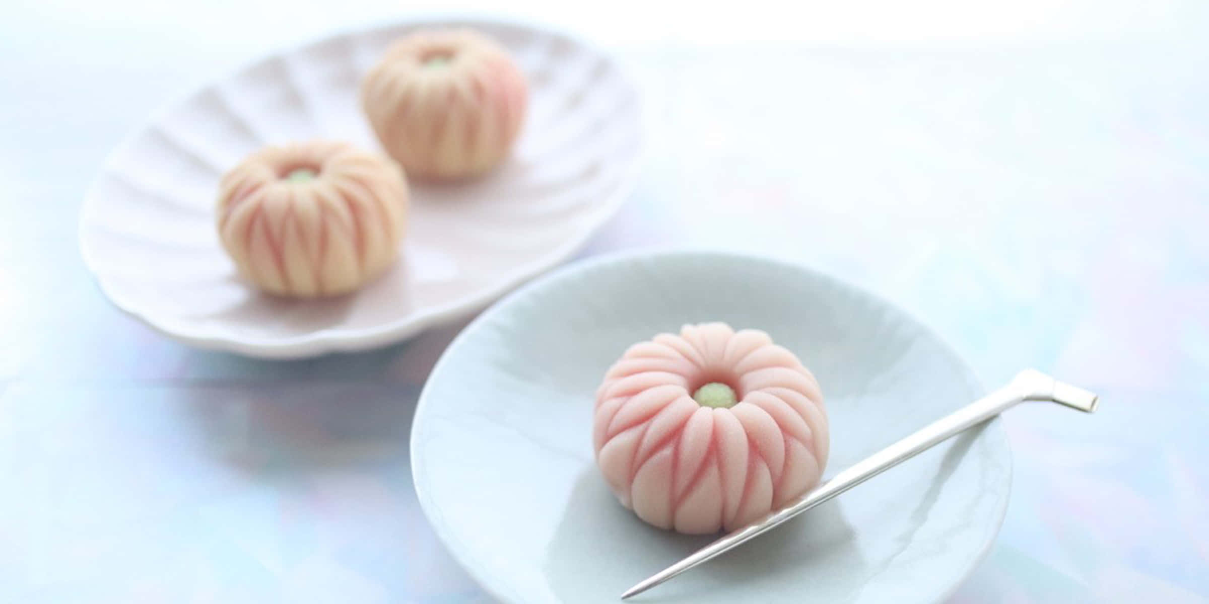 Japanese Sweets 桌布 壁紙 — 三個精緻的粉紅色和白色南瓜形麻糬甜點，優雅地擺放在白色盤子上，配以銀湯匙。