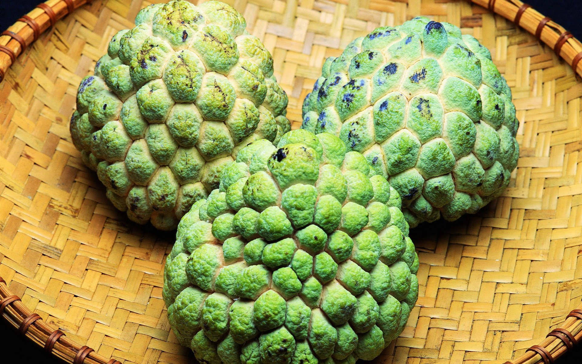 Fruit 桌布 壁紙 — 三個綠色帶刺的刺果番荔枝果實放在一個編織竹籃中，伴隨著溫暖的金色光線。