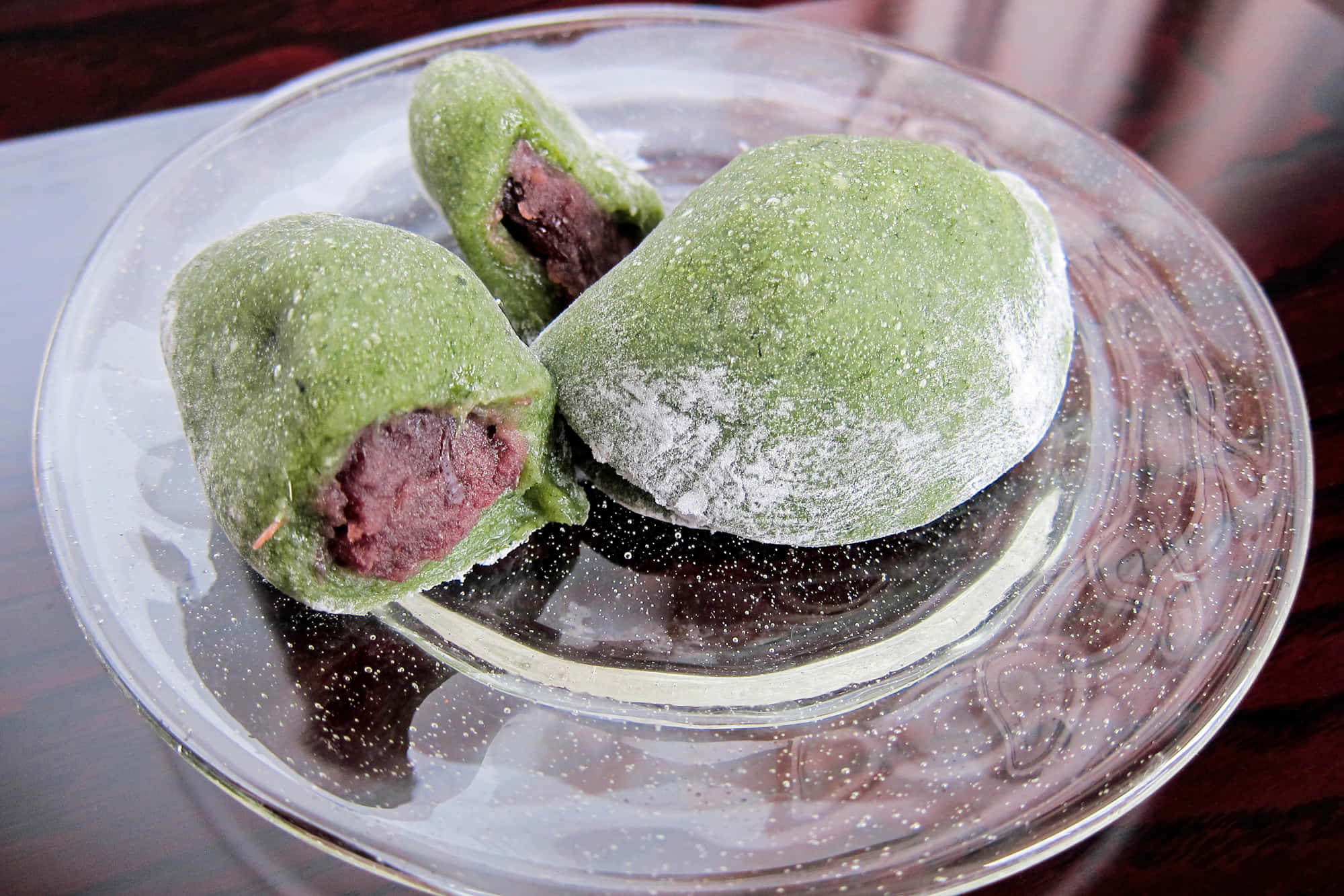 Japanese Sweets 桌布 壁紙 — 三個綠色抹茶麻糬，紅豆餡，撒上糖粉，放在華麗的玻璃盤上。