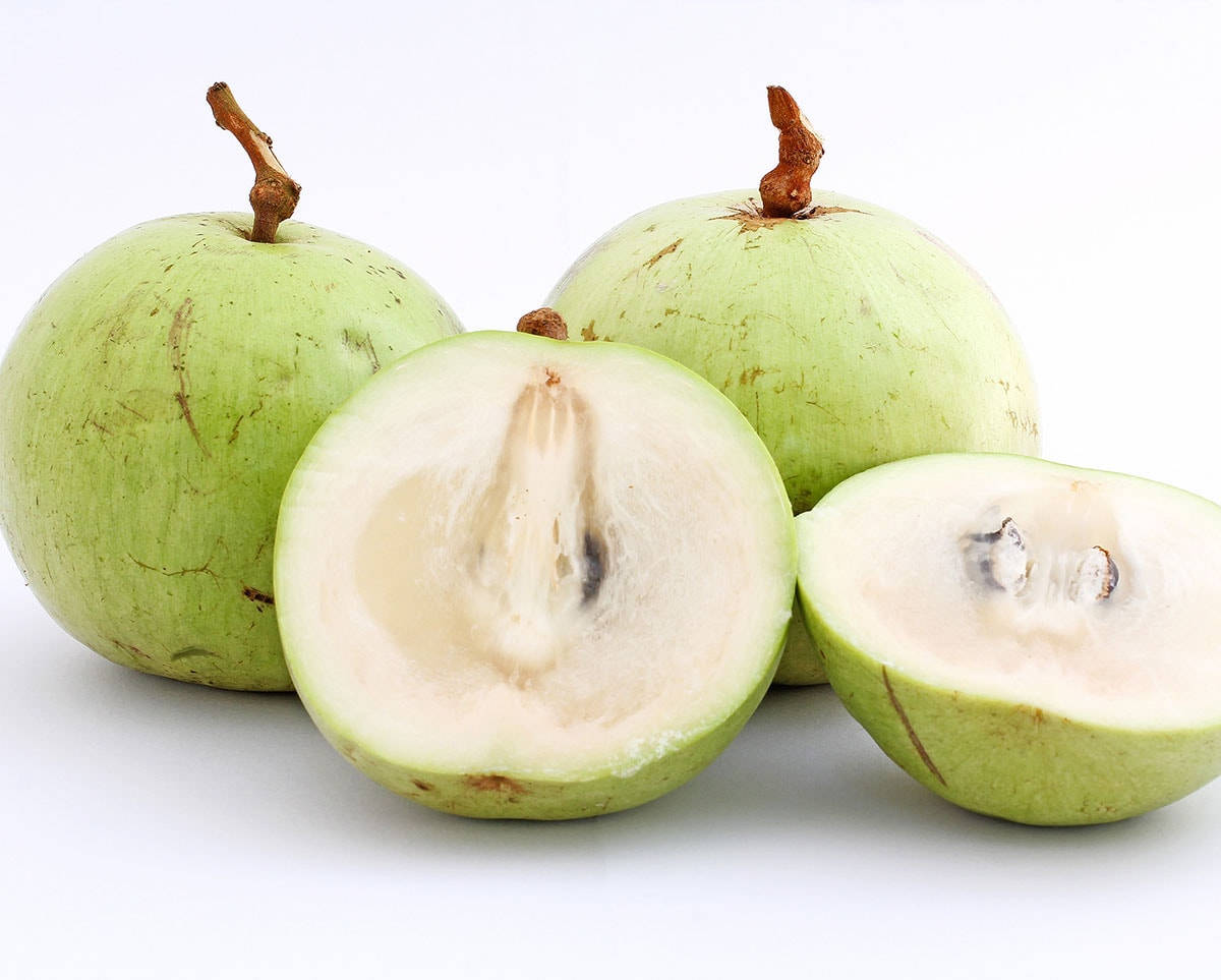Fruit 桌布 壁紙 — 三個綠色芭樂，其中一個切半，露出淡色果肉和種子，背景為純白色。