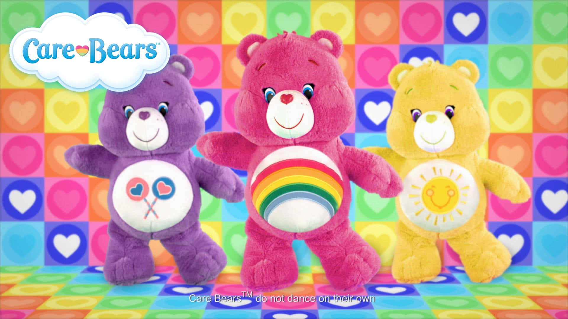 彩虹熊 桌布 壁紙 — 三個色彩繽紛的 Care Bears 毛絨玩具微笑著站在充滿活力的格子心形背景前。