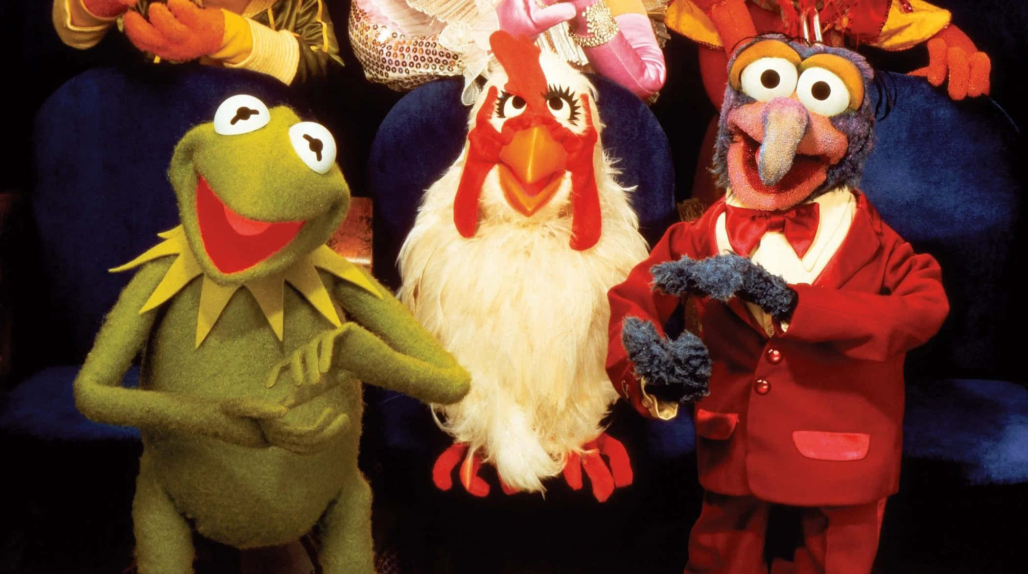 Animal Muppet 桌布 壁紙 — 三個色彩繽紛的 Muppet 角色在深藍色沙發上愉快地擺姿勢，表情豐富，服裝鮮豔。