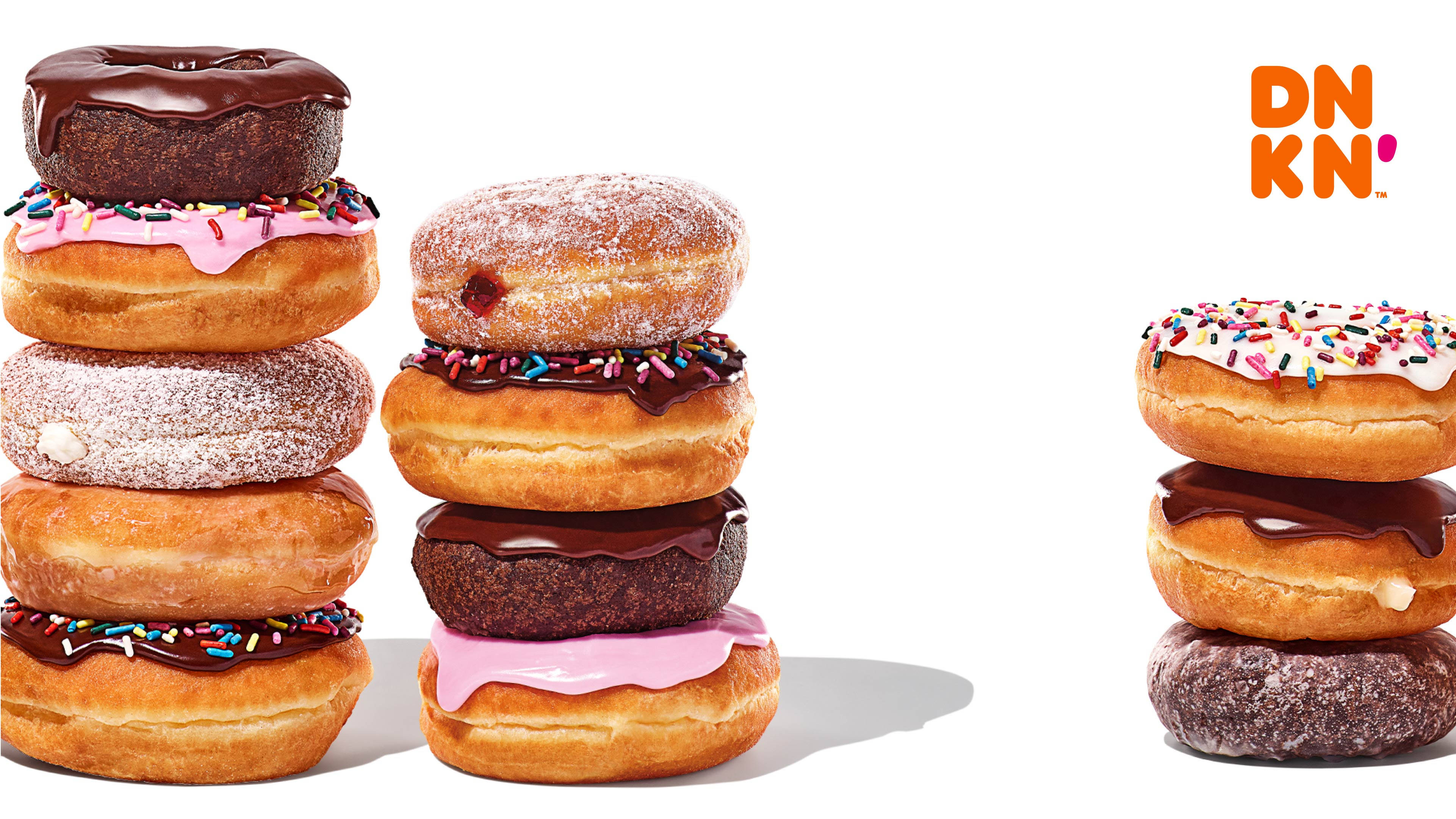 donuts 桌布 壁紙 — 三個色彩繽紛的堆疊，包含各種釉面巧克力灑粉和糖粉甜甜圈，背景為潔淨的白色。