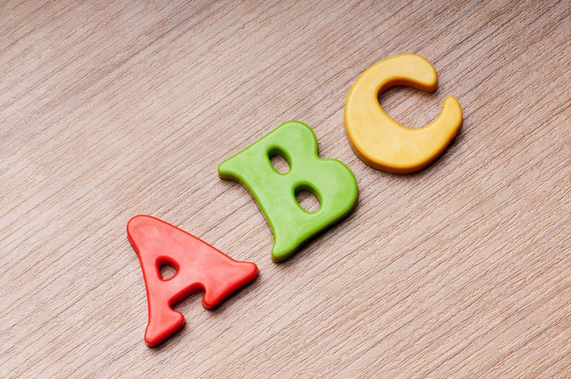 abc 桌布 壁紙 — 三個色彩繽紛的黏土字母ABC對角排列在淺色木質表面上。