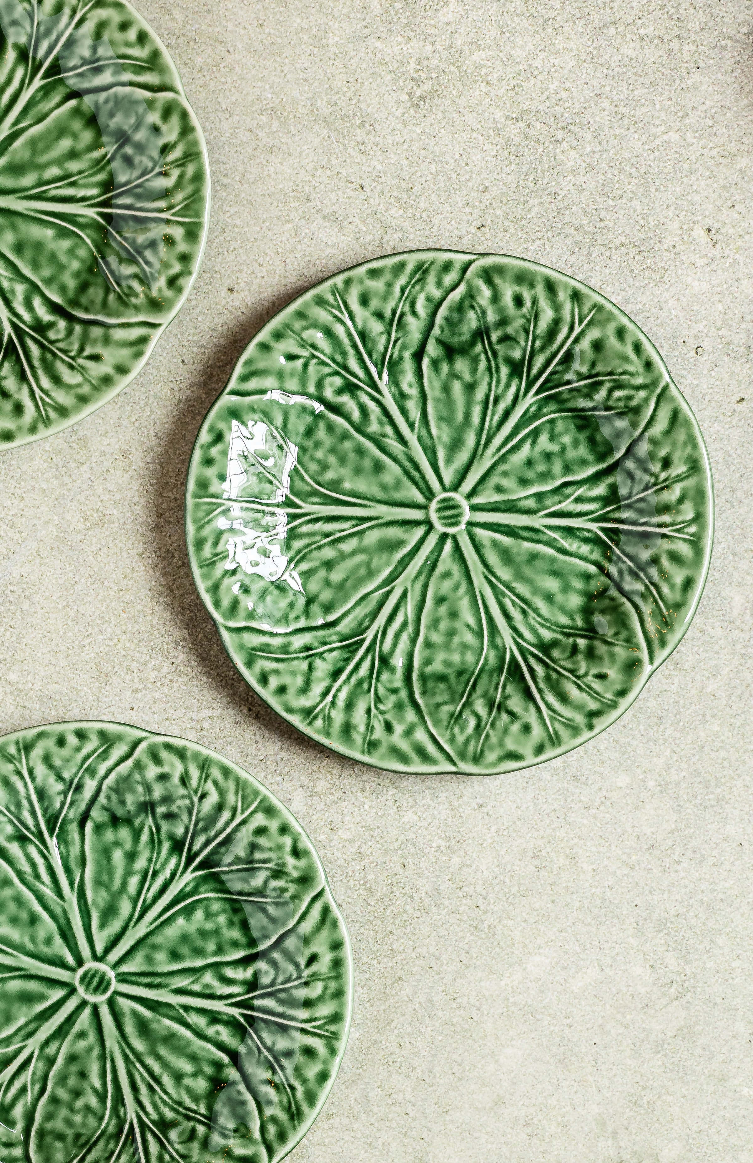 Aesthetic Green Minimal 桌布 壁紙 — 三個蓮葉形狀的綠色陶瓷盤放在有紋理的米色表面上。