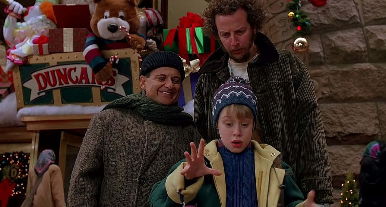 Home Alone 桌布 壁紙 — 三個角色在節日假期場景中，配有聖誕裝飾和 Duncan's 玩具店招牌。