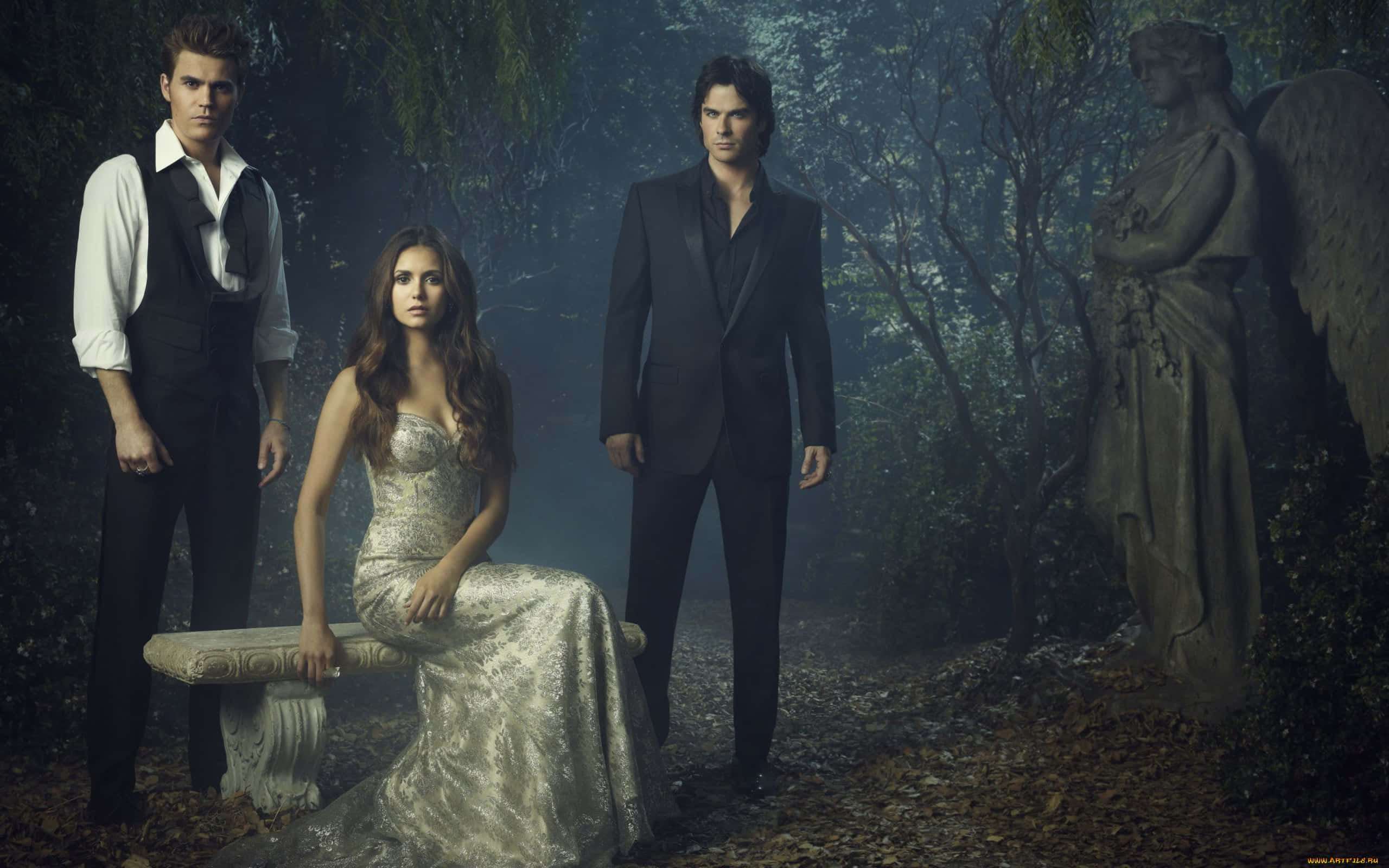 Vampire Diaries Desktop 桌布 壁紙 — 三個身穿正式服裝的人物站在霧氣瀰漫的森林中，旁邊有一座石天使雕像和長椅。