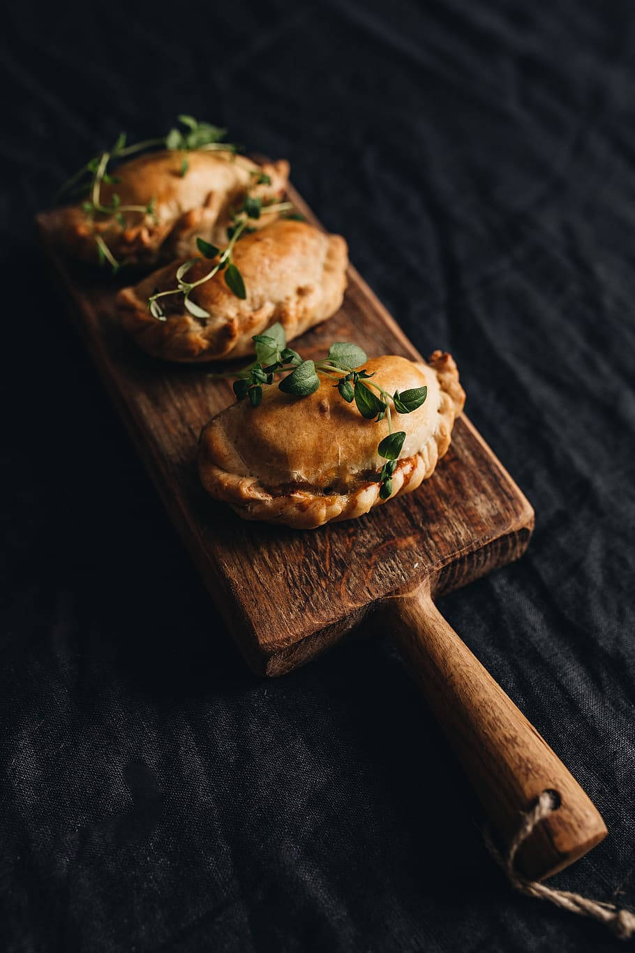 Pastry 桌布 壁紙 — 三個金黃色手派，飾以新鮮百里香，放在質樸木板上，襯以深色紋理背景。