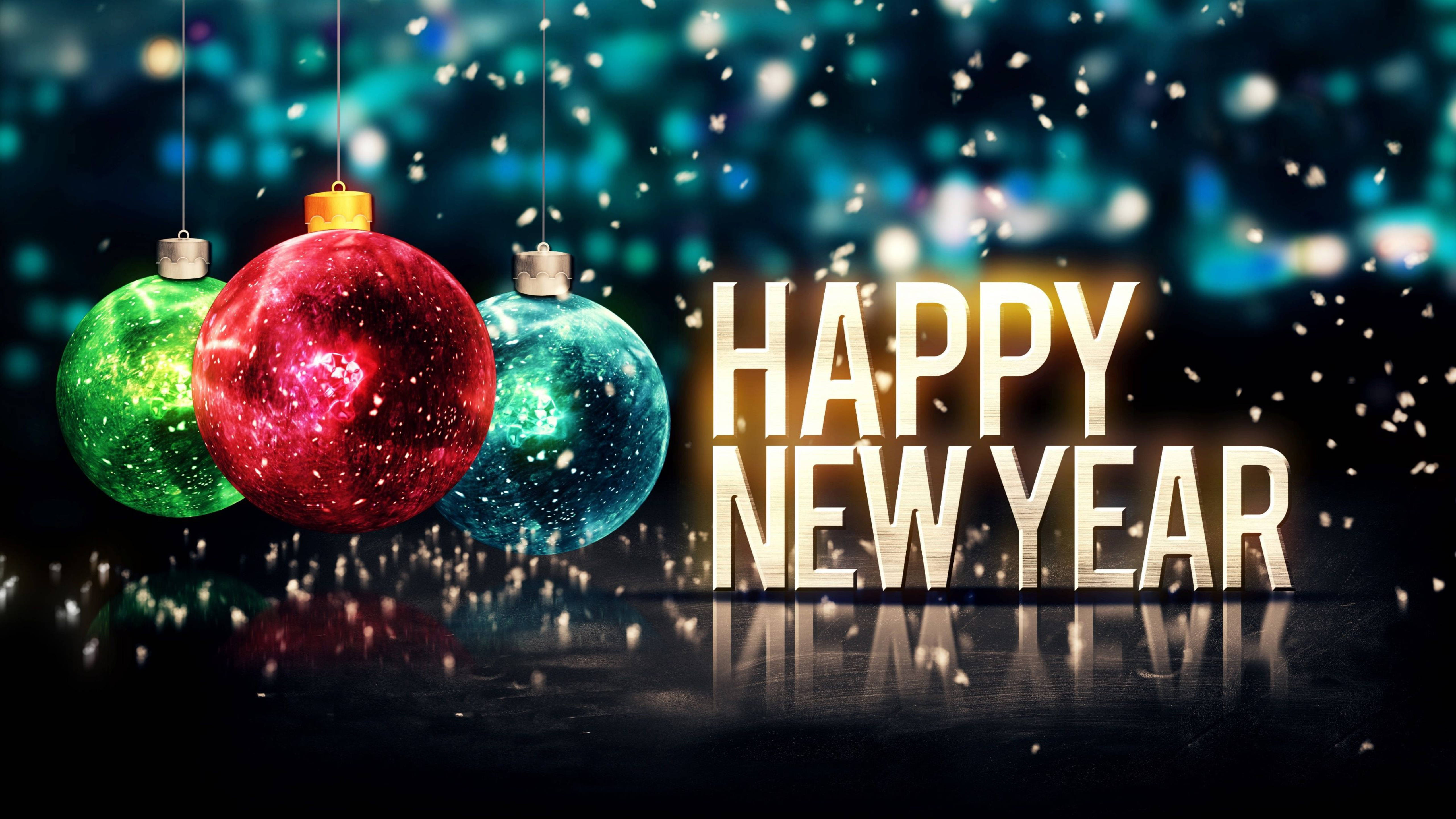New 桌布 壁紙 — 三個閃閃發光的節日裝飾品懸掛在發光的「HAPPY NEW YEAR」文字上方，五彩紙屑在散景城市背景下飄落。