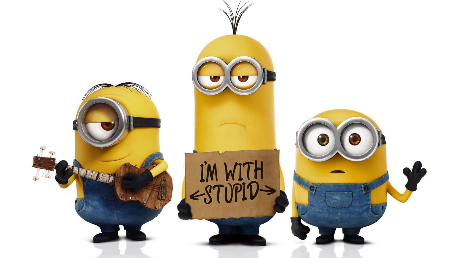 Minion 桌布 壁紙 — 三個黃色小小兵身穿藍色吊帶褲，在白色背景前擺姿勢，一個彈奏烏克麗麗，一個舉著寫有「I'M WITH STUPID」的牌子，一個揮手。