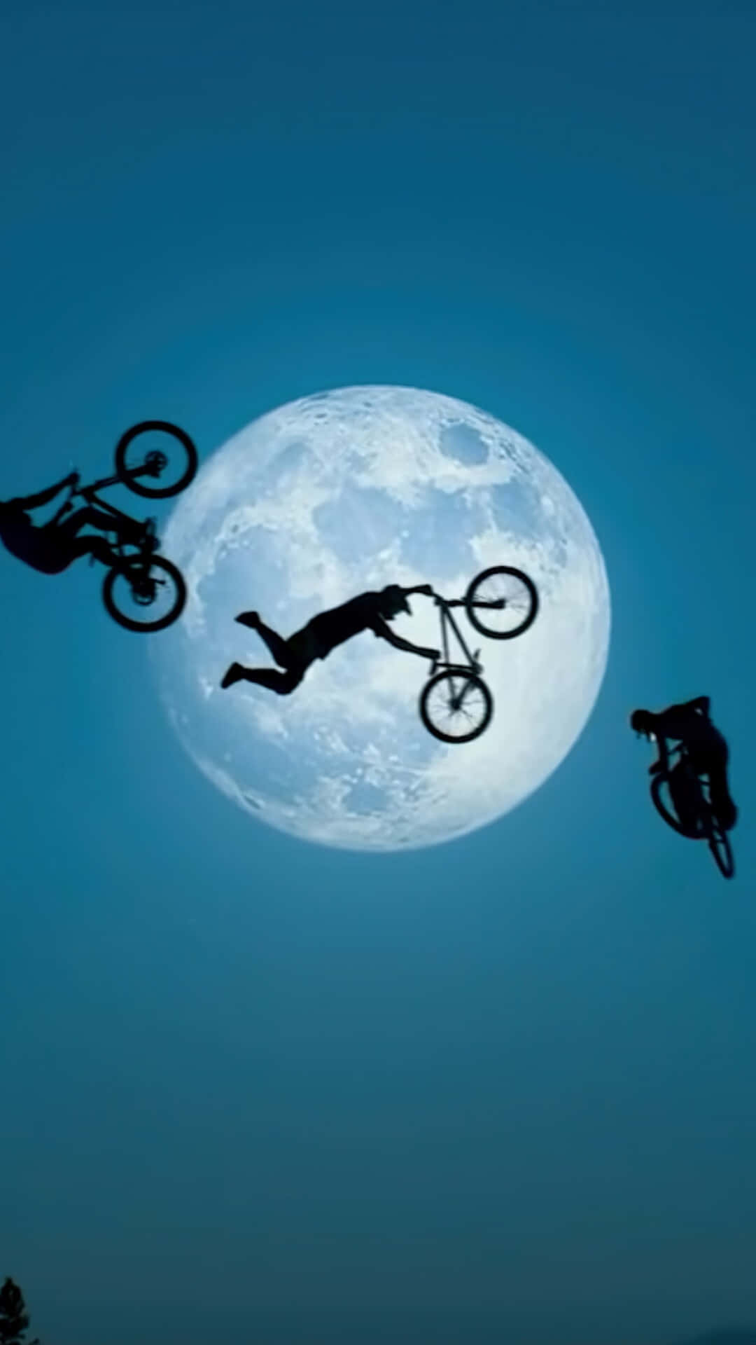 bmx 桌布 壁紙 — 三名BMX車手在深藍色暮色天空下，以剪影姿態翱翔於一輪巨大發光的月亮前。