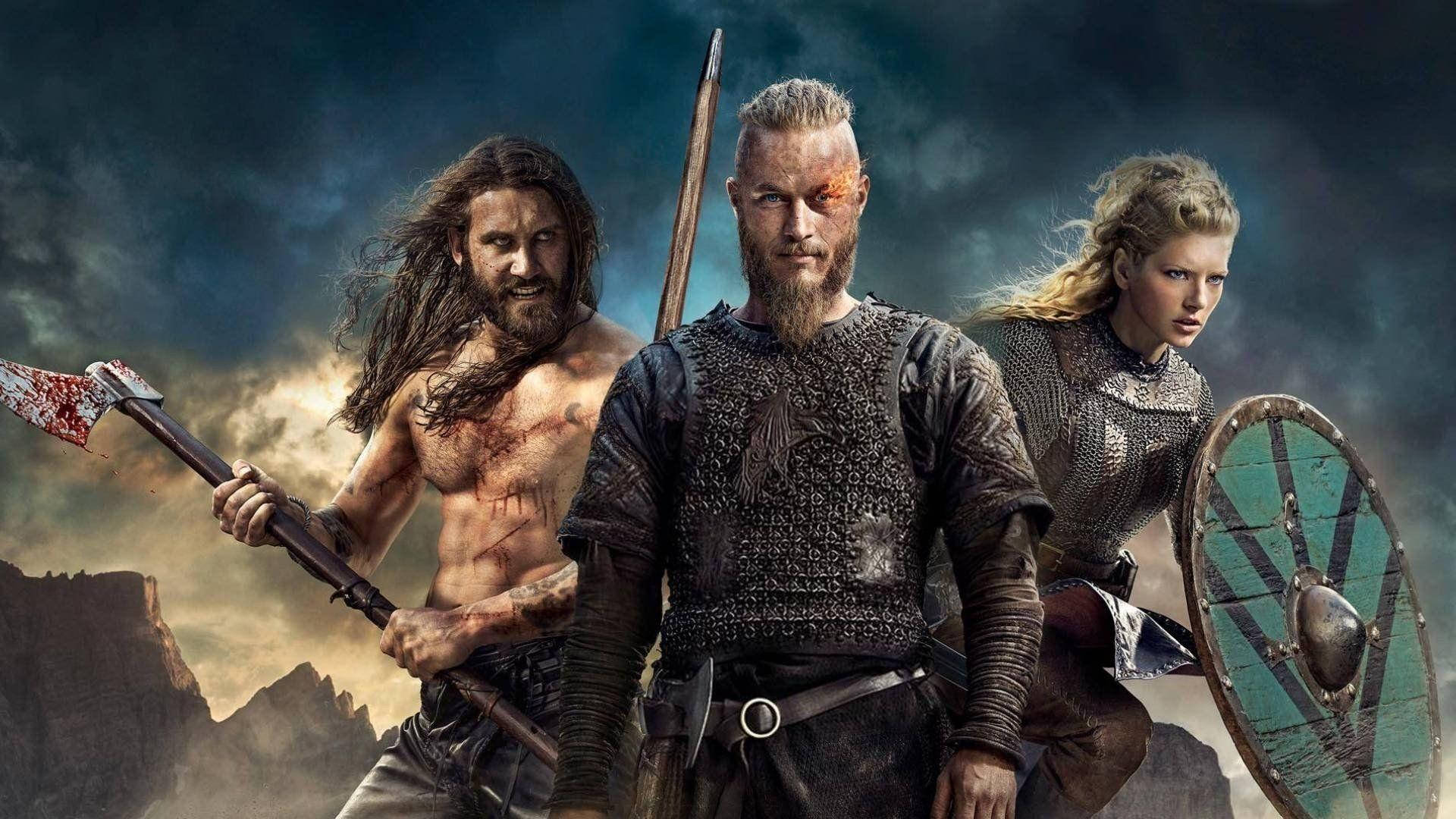 Vikings 桌布 壁紙 — 三名兇猛的維京人準備好戰鬥，背景是風暴天空和崎嶇的山脈。