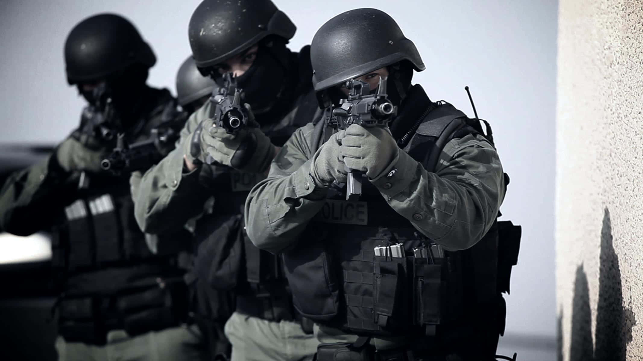 Swat 桌布 壁紙 — 三名全副武裝的警察戰術人員以專注的強度瞄準武器，對著一面素牆。