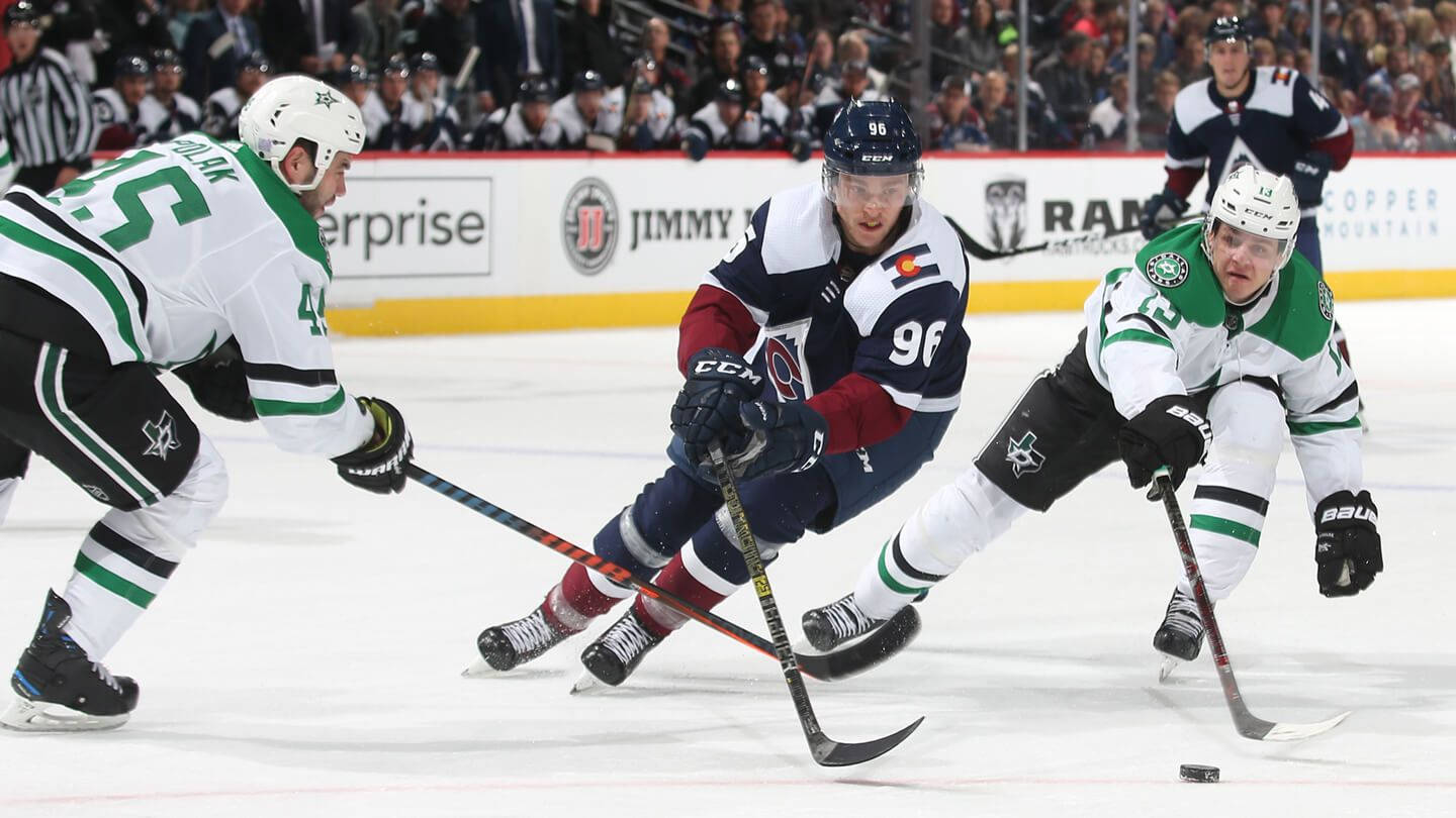 Dallas Stars 桌布 壁紙 — 三名冰球運動員在明亮的冰場上進行職業比賽時激烈爭奪冰球。