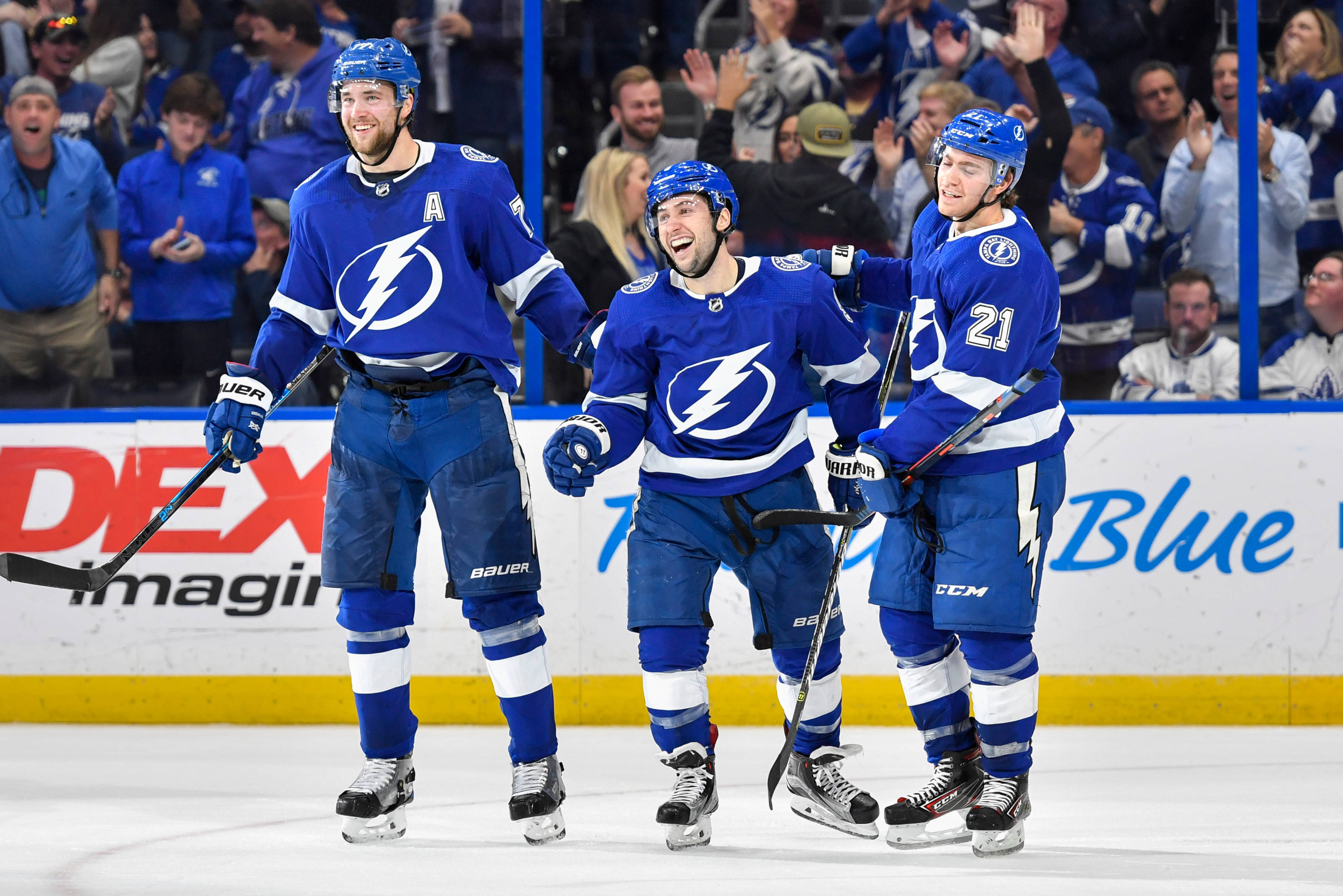 hockey 桌布 壁紙 — 三名坦帕灣閃電隊冰球球員在冰上慶祝進球，背景有球迷歡呼。