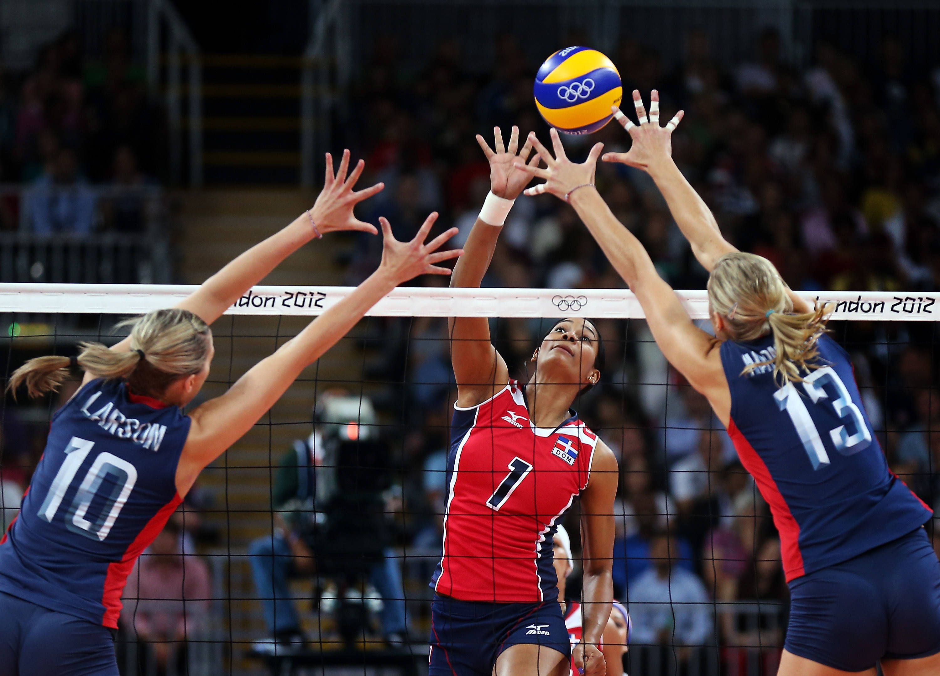 Volleyball 桌布 壁紙 — 三名女子排球運動員在2012年倫敦奧運會的激烈比賽中跳躍到網前。