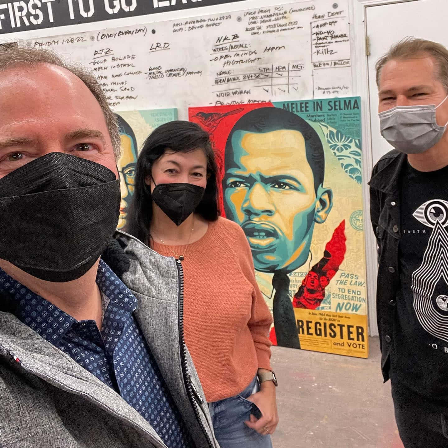 政治 桌布 壁紙 — 三名戴著口罩的人士在馬丁·路德·金的鮮明壁畫前擺姿勢，背後牆上有抗議標語和手寫筆記。
