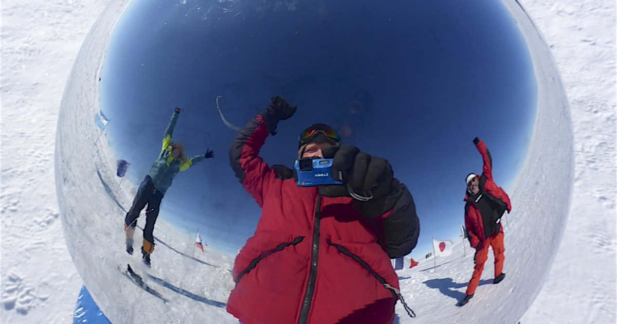 South Pole 桌布 壁紙 — 三名滑雪者在雪坡上慶祝勝利，透過魚眼鏡頭捕捉，映照出廣闊的藍天。