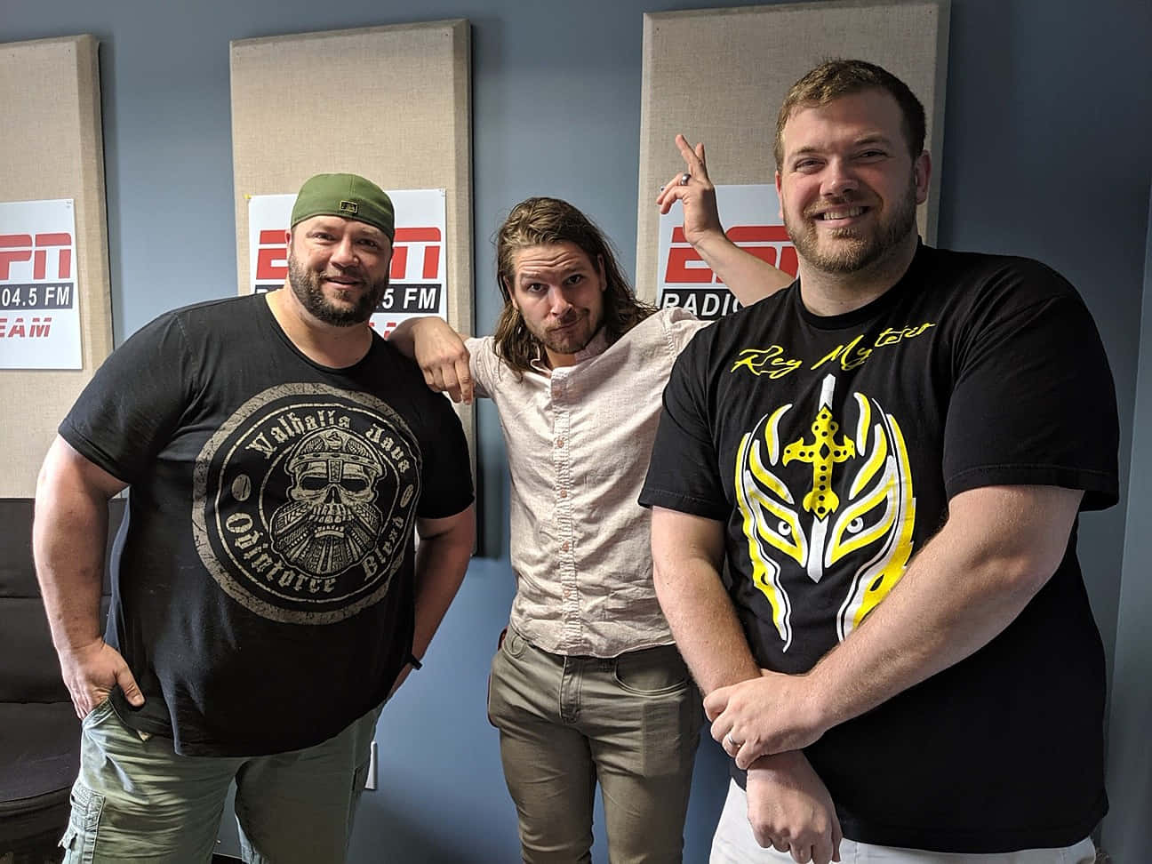 American 桌布 壁紙 — 三名男子在一個背後牆上帶有ESPN Radio品牌的電台錄音室中愉快地擺姿勢。