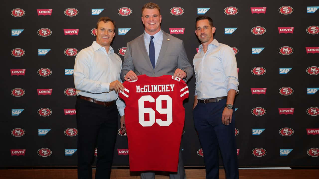 Mike Mcglinchey 桌布 壁紙 — 三名男子在品牌背景前，手持一件印有 McGlinchey 69 的紅色舊金山 49 人隊球衣擺姿勢。