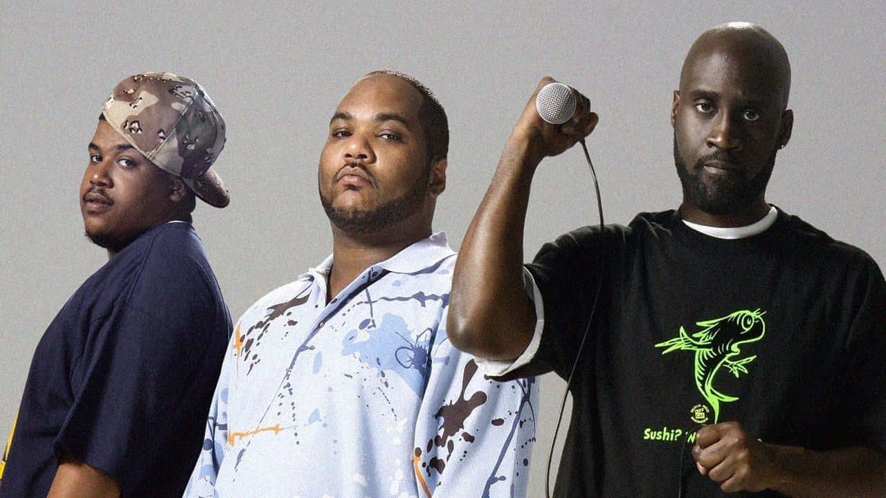 De La Soul 桌布 壁紙 — 三名男子在純灰色背景前自信地擺姿勢，其中一人手持麥克風，身穿壽司魚圖案T恤。