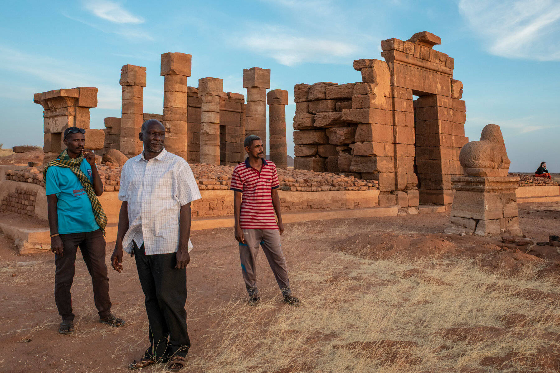 Sudan 桌布 壁紙 — 三名男子站在古老的石頭廢墟前，腳下是乾草，頭上是晴朗的藍天。