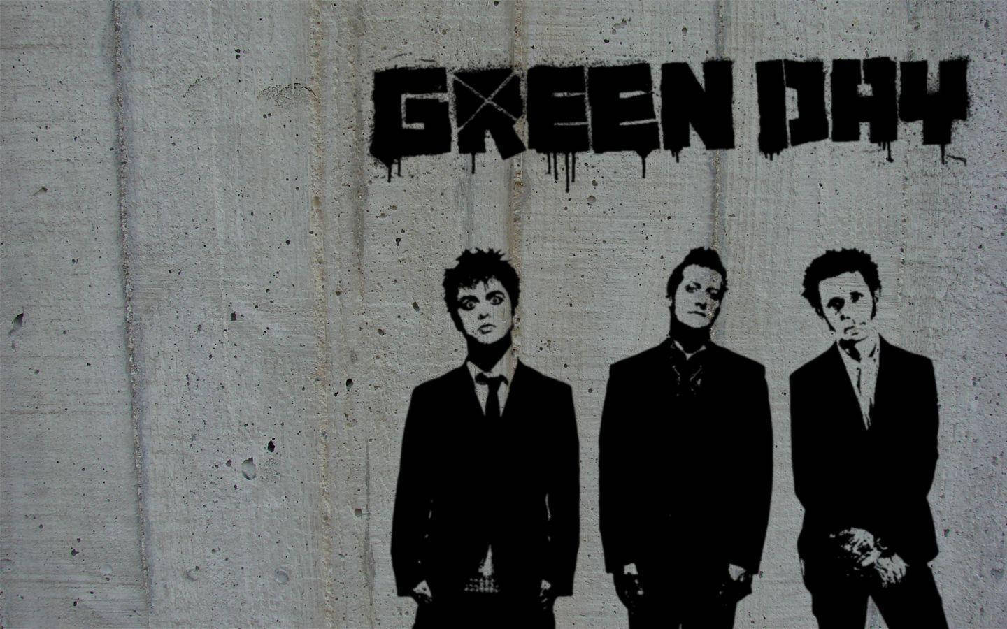 Green Day 桌布 壁紙 — 三名穿西裝的男子站在一個滴落的「GREEN DAY」塗鴉標籤下方，背景是風化的混凝土牆。