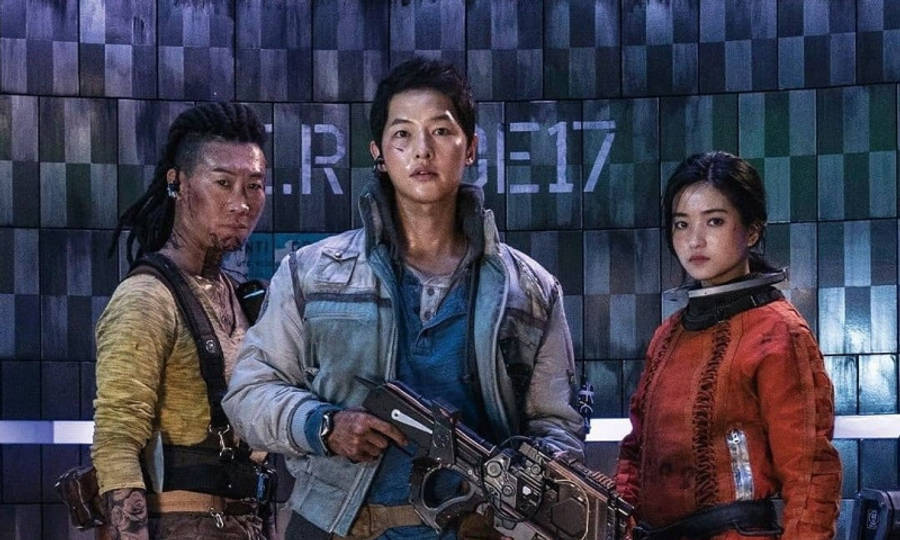 Space Sweepers 桌布 壁紙 — 三名粗獷的未來戰士手持武器，站在一面顯示 'R.E.17' 的格子牆前準備就緒。