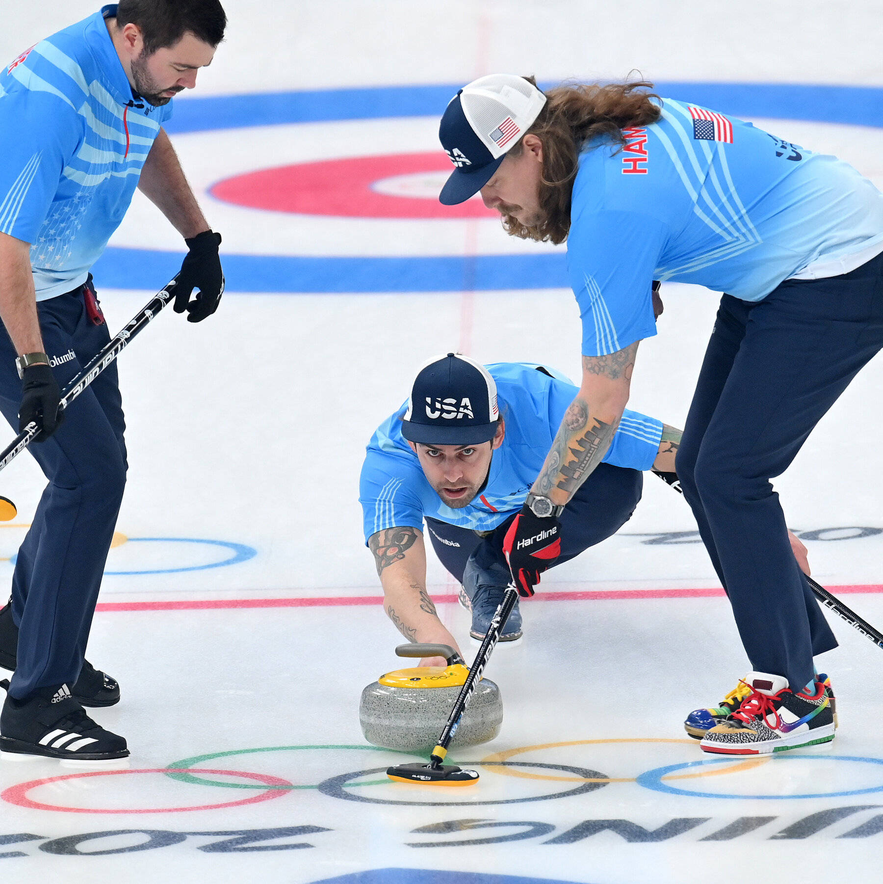 Olympics 桌布 壁紙 — 三名美國冰壺運動員專注地看著其中一人將石頭滑過奧運冰場，隊友則在掃冰。