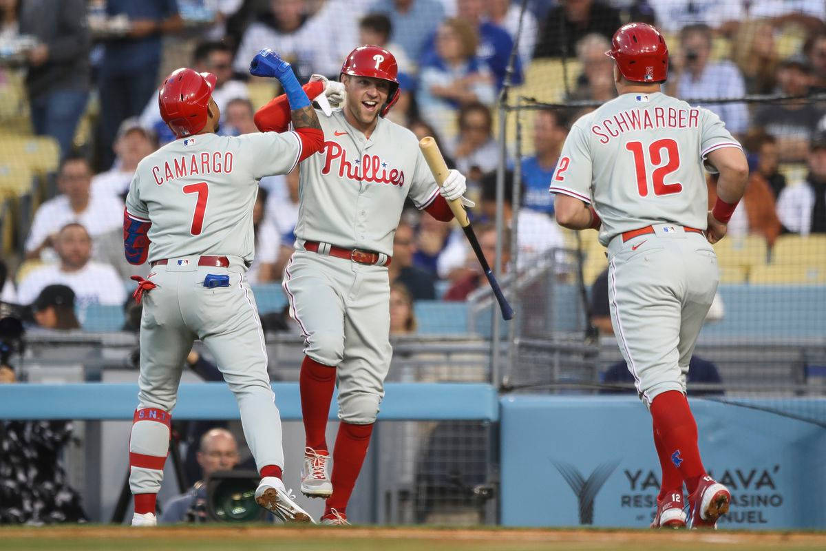 Phillies 桌布 壁紙 — 三名費城費城人棒球選手在陽光明媚的球場上以擊掌和歡樂的表情慶祝全壘打。