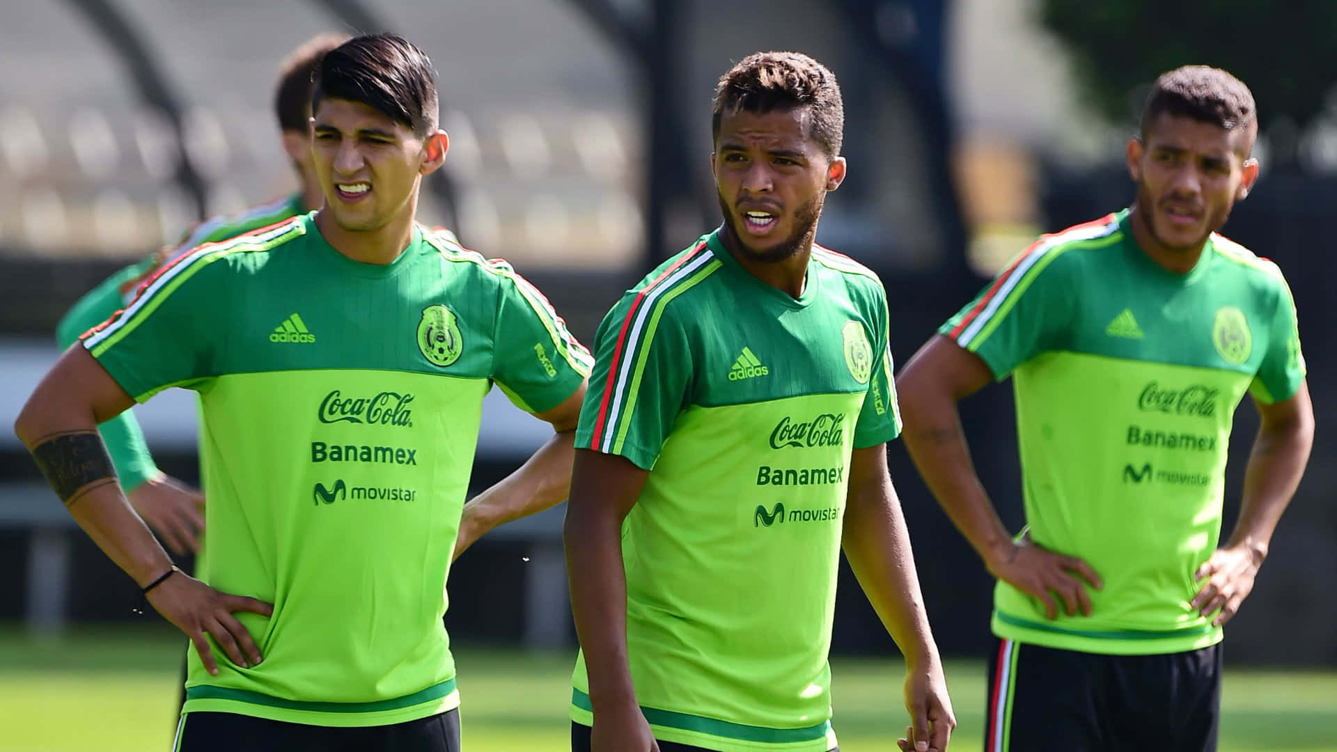 Mexico Soccer 桌布 壁紙 — 三名身穿亮綠色訓練服的墨西哥足球員在陽光明媚的日子裡站在草地上訓練。