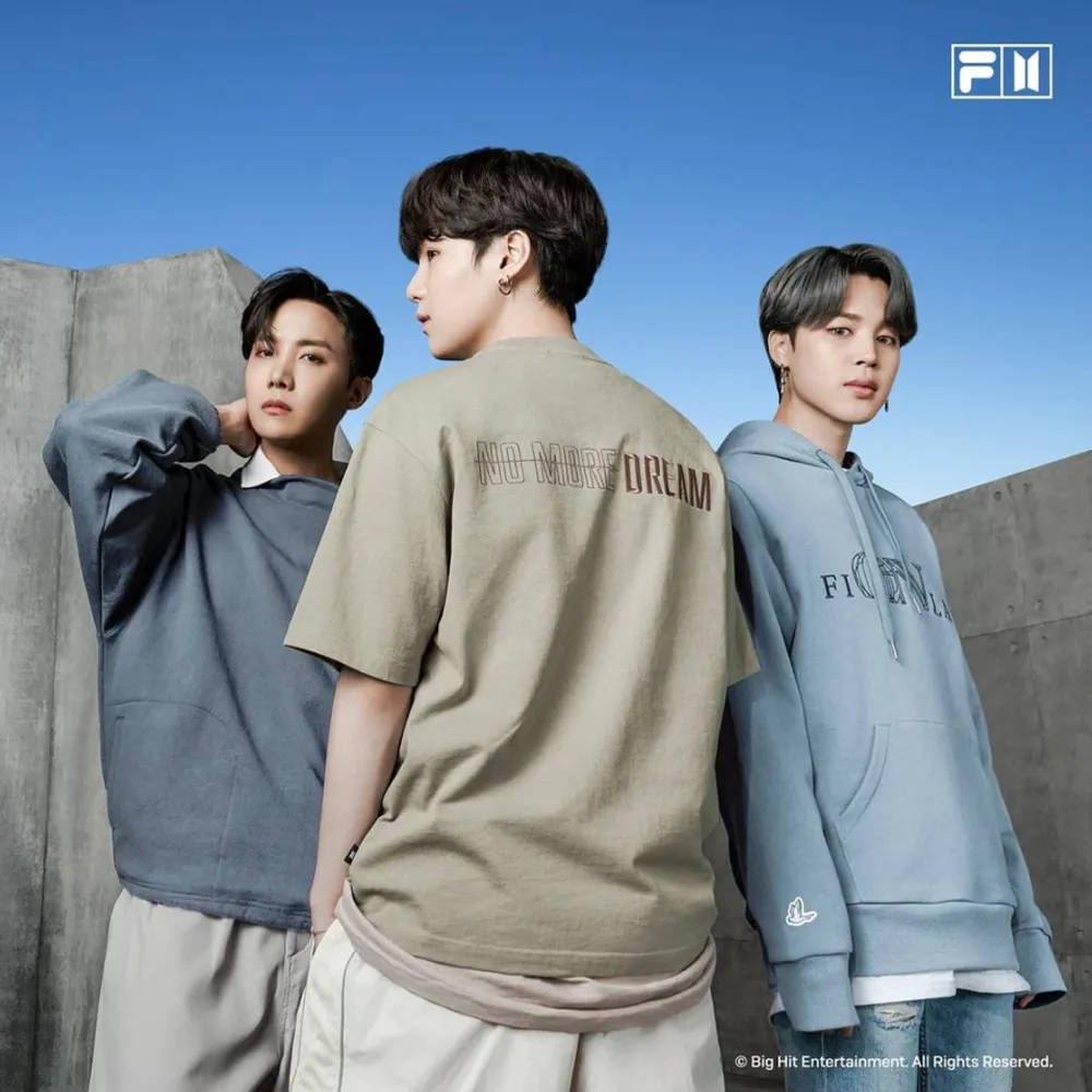 Fila 桌布 壁紙 — 三名身穿休閒街頭服的年輕男子在晴朗藍天下以混凝土牆為背景擺姿勢。