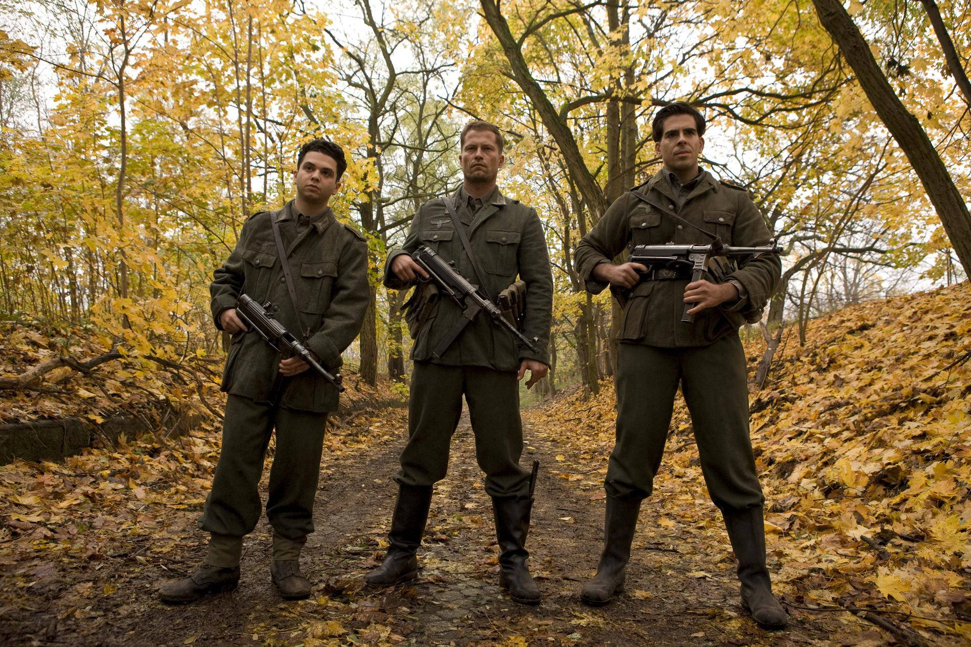 Inglourious Basterds 桌布 壁紙 — 三名身穿橄欖綠軍裝的士兵在鋪滿金色秋葉的森林中持步槍警戒。