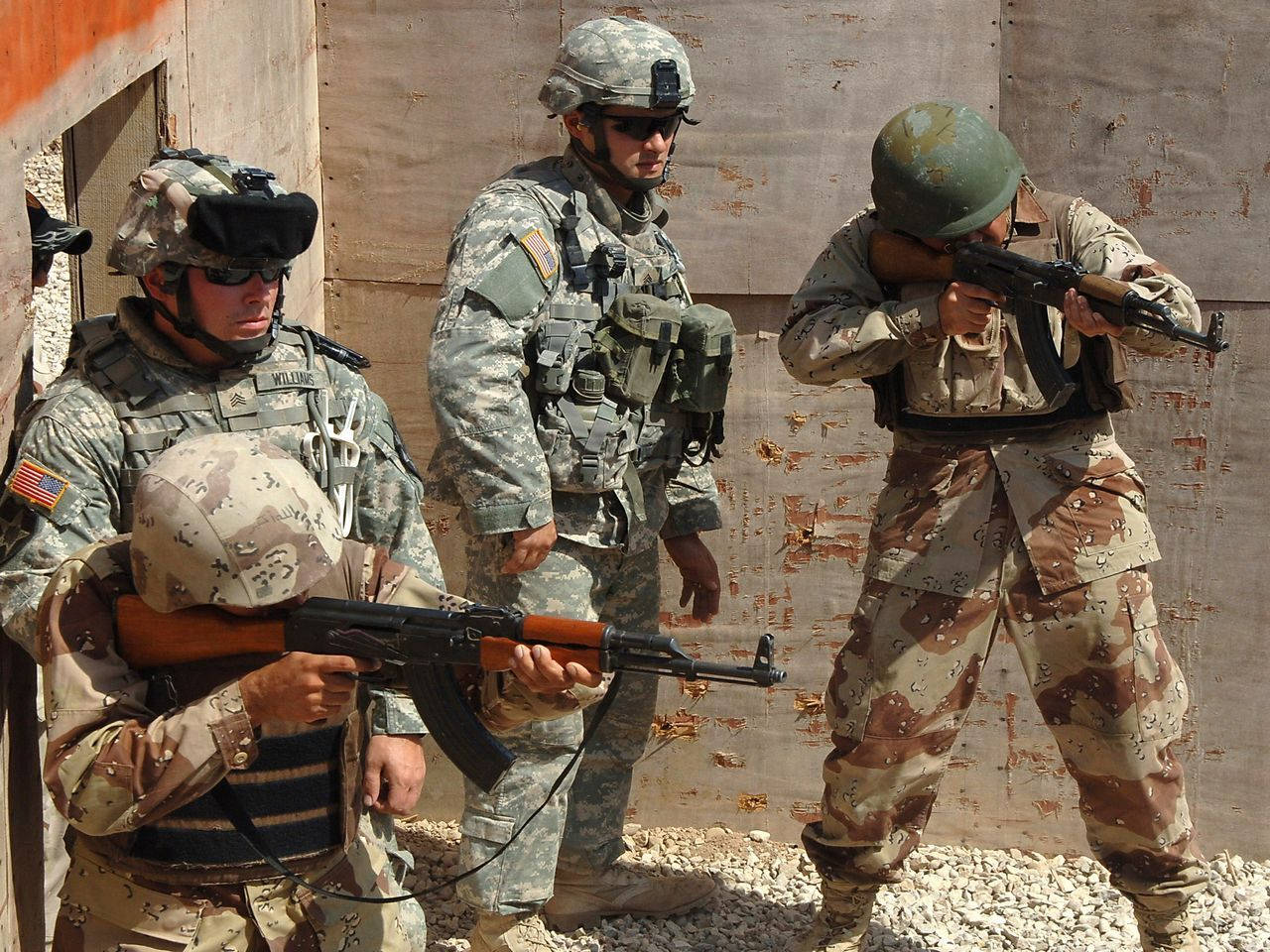 US 桌布 壁紙 — 三名身穿沙漠迷彩服的士兵在明亮的日光下，於塵土飛揚的訓練區域持步槍警戒。
