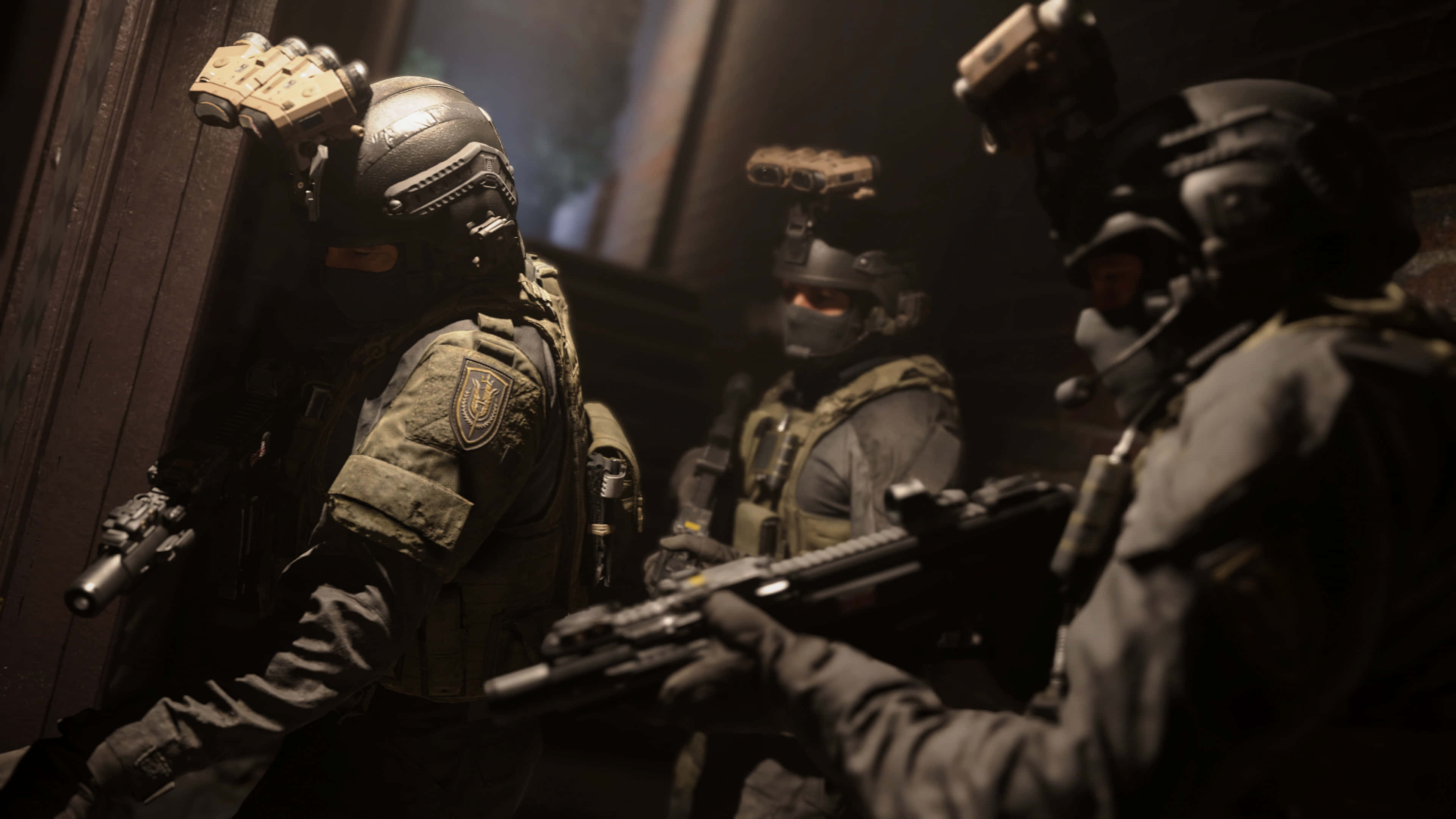 HD Call Of Duty Modern Warfare 桌布 壁紙 — 三名身穿深色裝備的重裝戰術士兵，手持武器謹慎地穿過光線昏暗的門口。