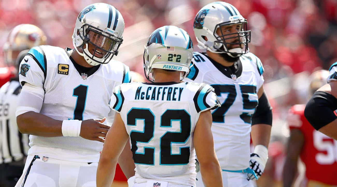 Christian Mccaffrey 桌布 壁紙 — 三名身穿白色球衣的卡羅萊納黑豹隊美式足球員在陽光明媚的球場上比賽期間聚在一起。