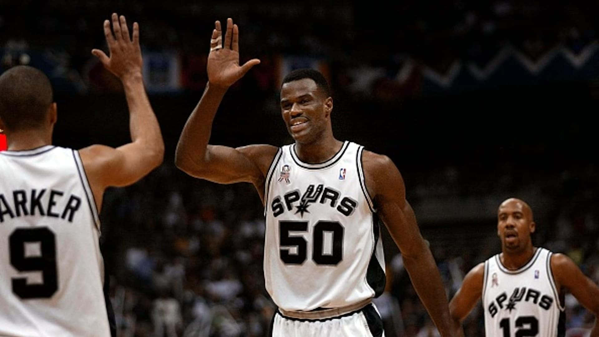 NBA 桌布 壁紙 — 三名身穿白色球衣的聖安東尼奧馬刺籃球運動員在明亮的場館燈光下比賽期間擊掌慶祝。