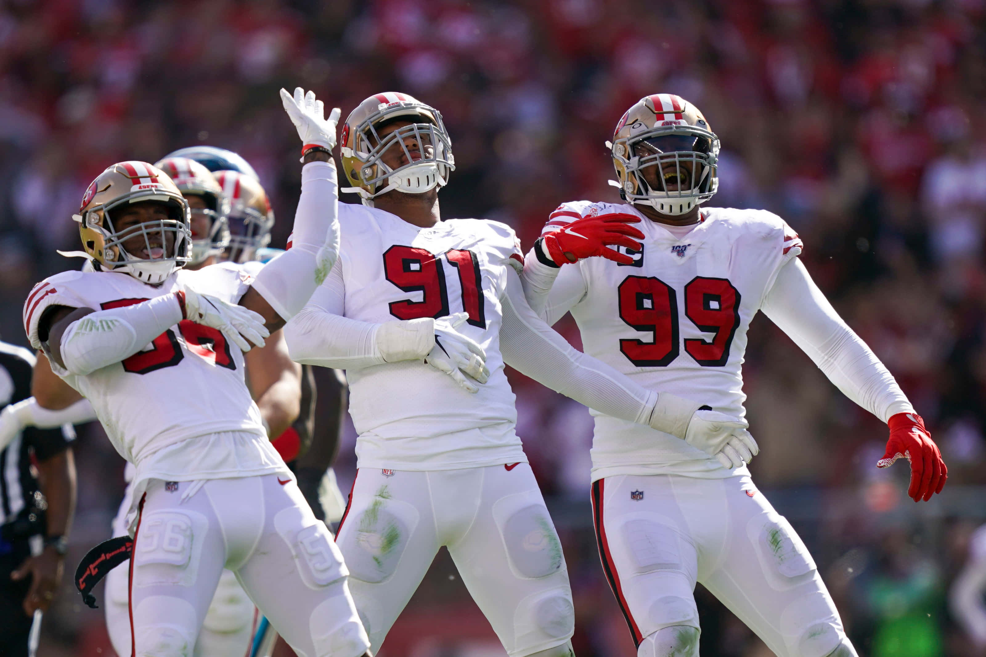 San Francisco 49ers 桌布 壁紙 — 三名身穿白色球衣的舊金山49人美式足球員在陽光明媚的球場上慶祝一次進攻，背景是模糊的人群。