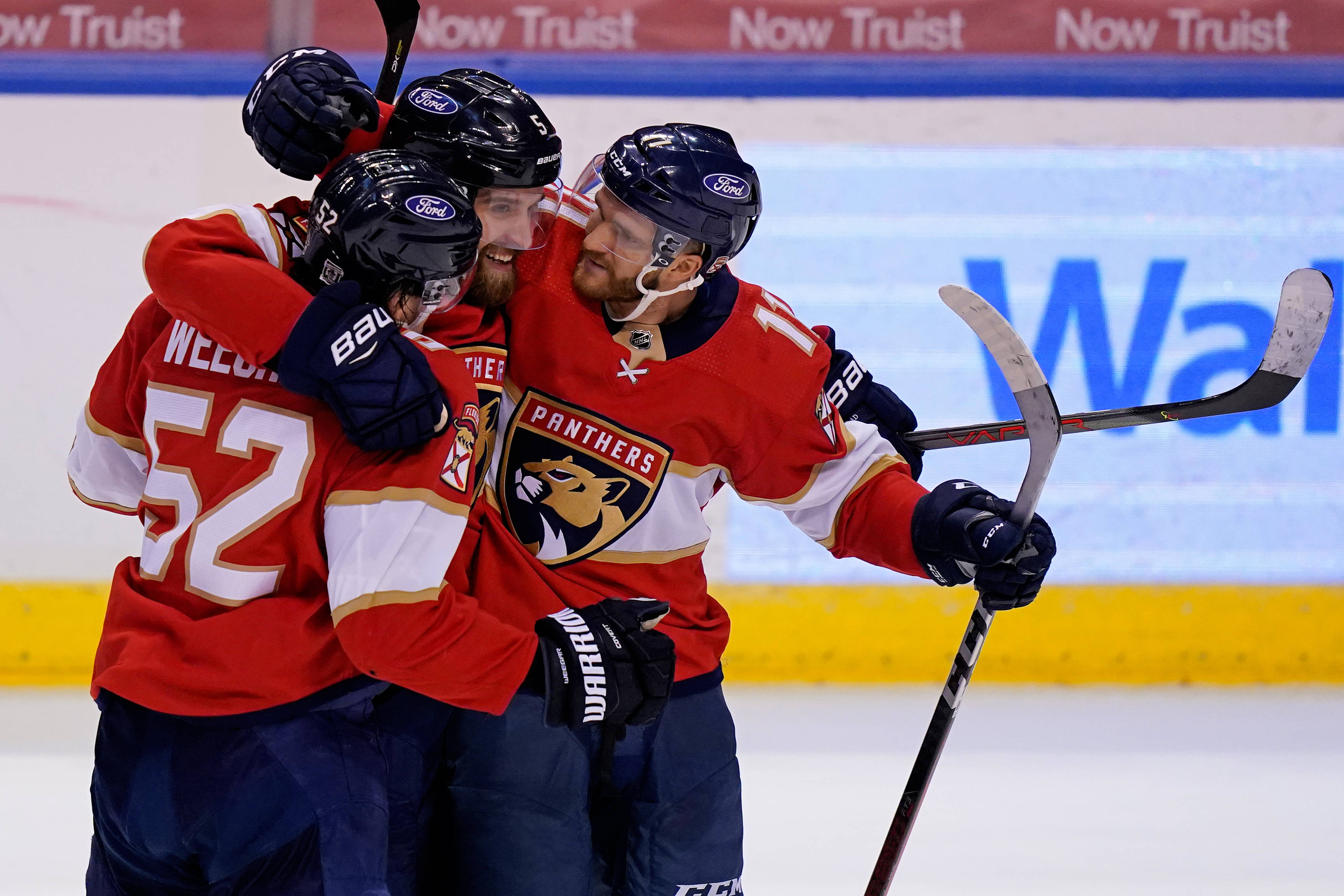 hockey 桌布 壁紙 — 三名身穿紅色球衣的佛羅里達美洲豹冰球球員在冰上脫下頭盔、高舉球棍慶祝進球。