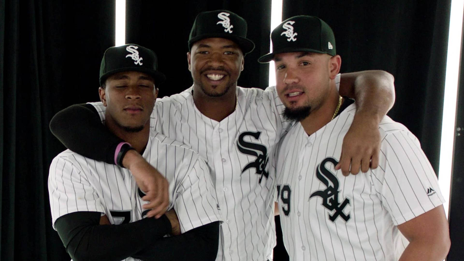 Chicago White Sox 桌布 壁紙 — 三名身穿細條紋球衣的芝加哥白襪棒球運動員微笑著互相搭肩，在黑色背景和明亮垂直燈光下合影。